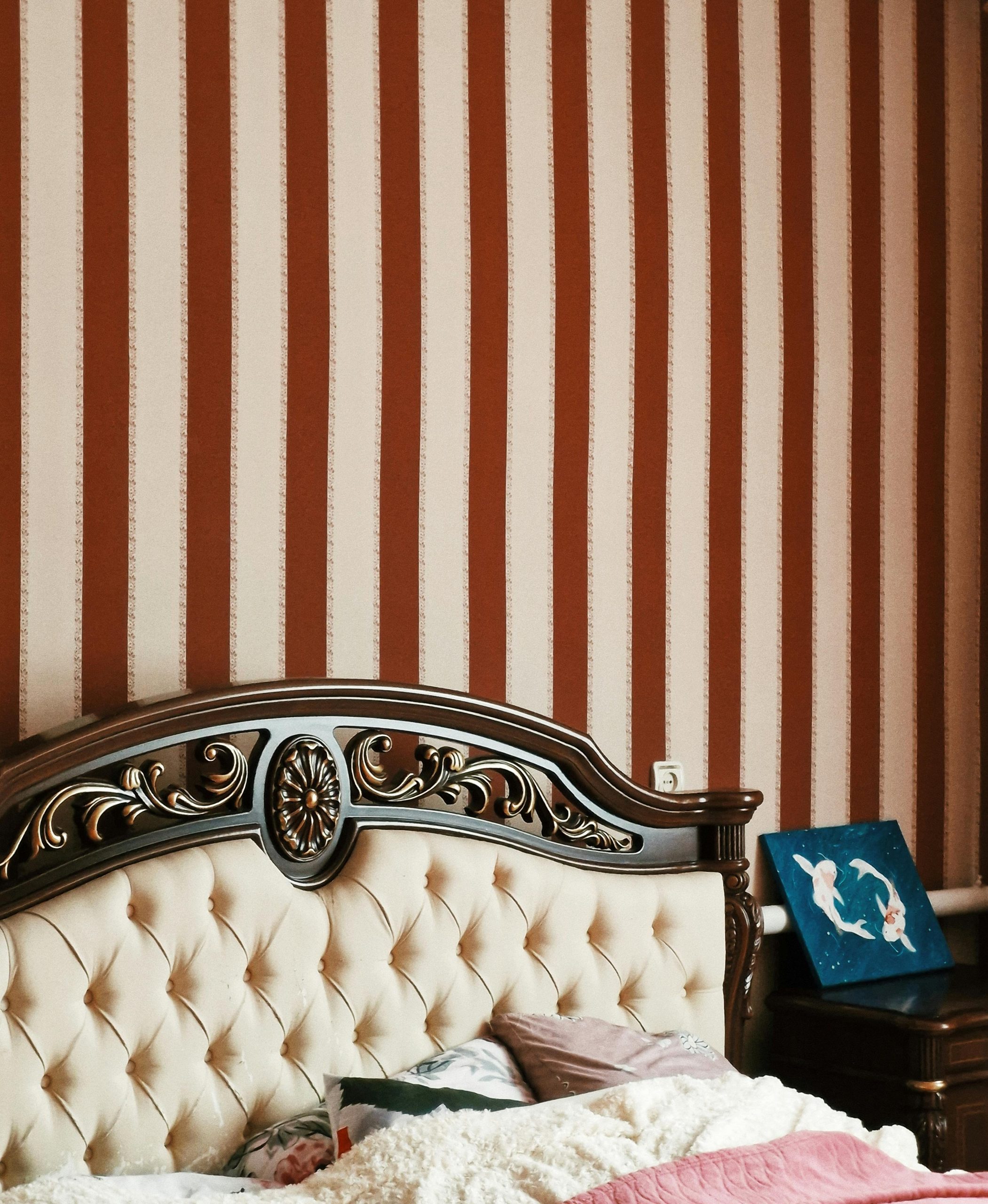 Luxurious bedroom featuring a carved wooden headboard and striped wallpaper for a classic look.