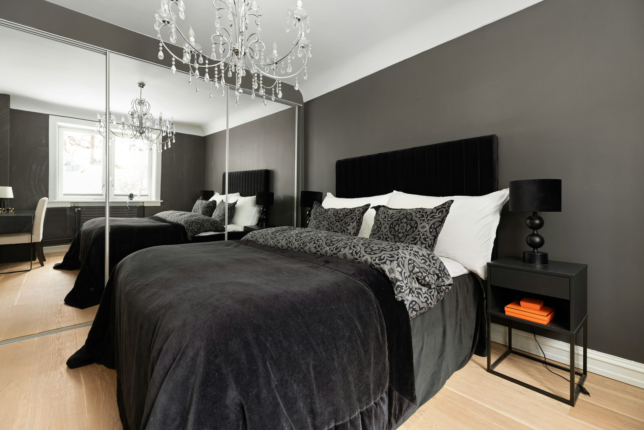 A bed room with a neatly made bed and a chandelier
