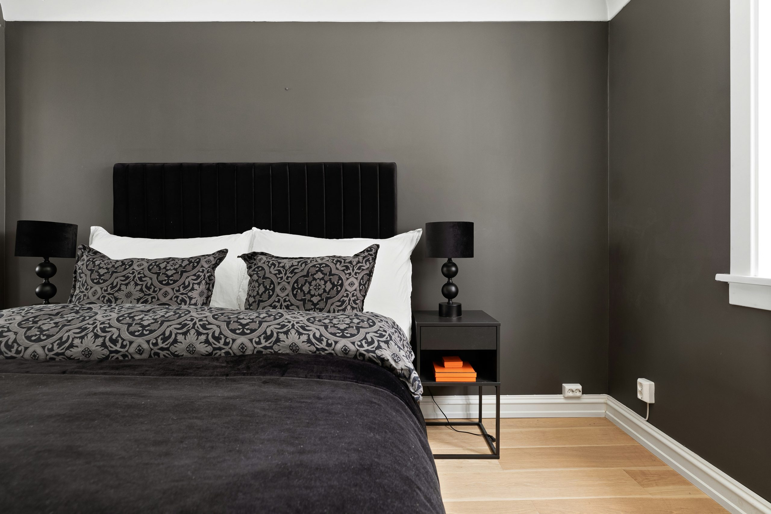 A bedroom with a bed, nightstands and a window