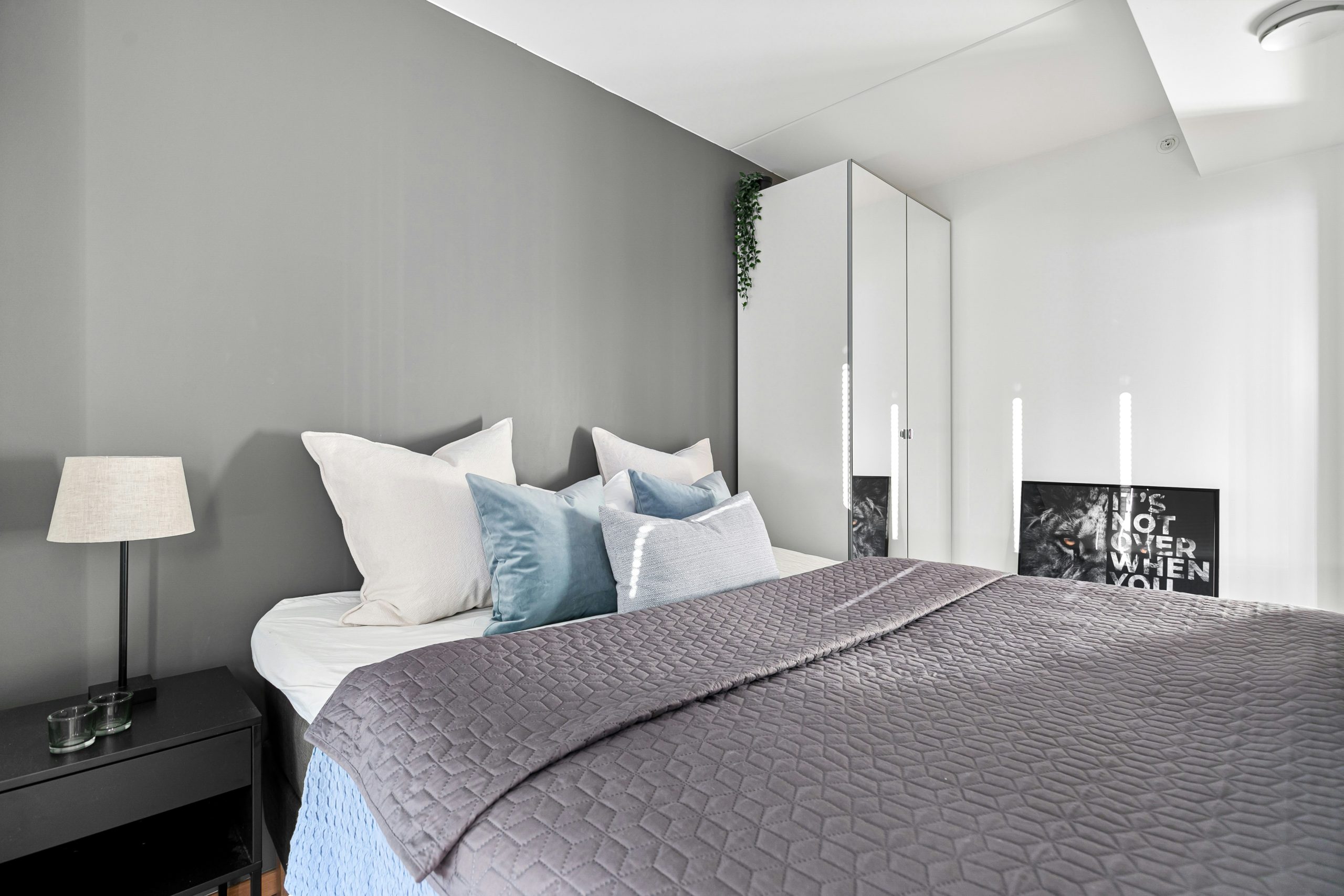 A bedroom with a large bed and a mirror on the wall