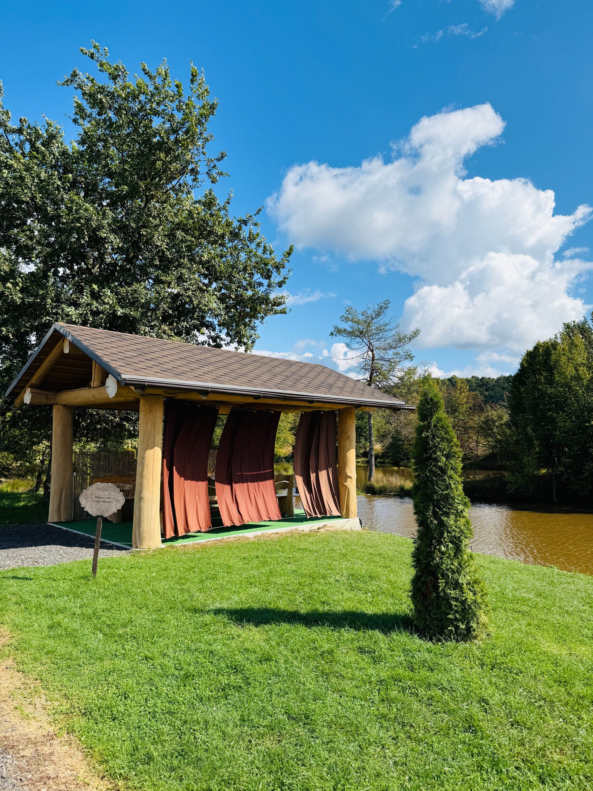 A charming gazebo by a peaceful lake under a bright summer sky, perfect for relaxation.