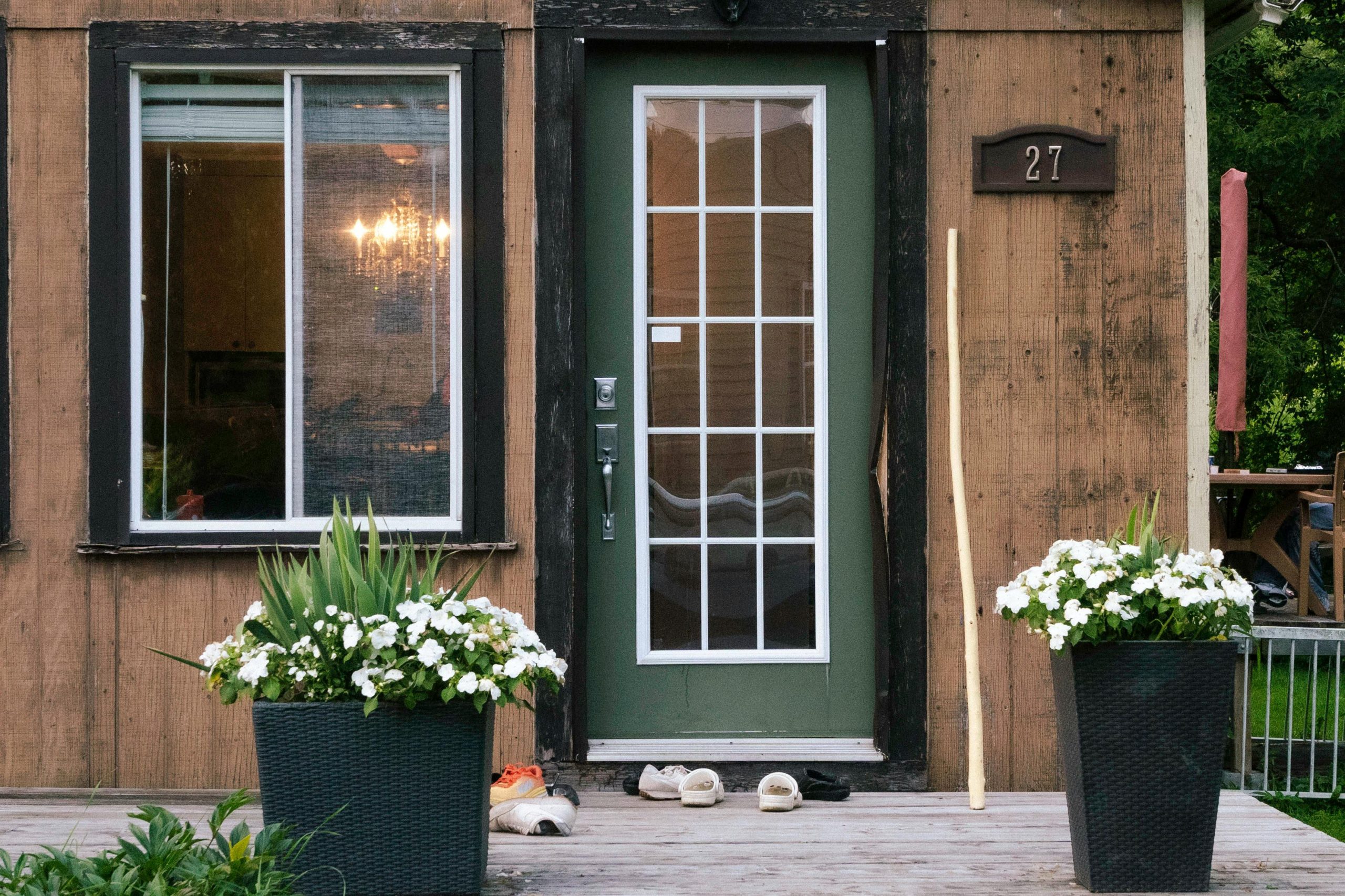 A charming rustic wooden house entrance with large potted flowers and inviting decor.