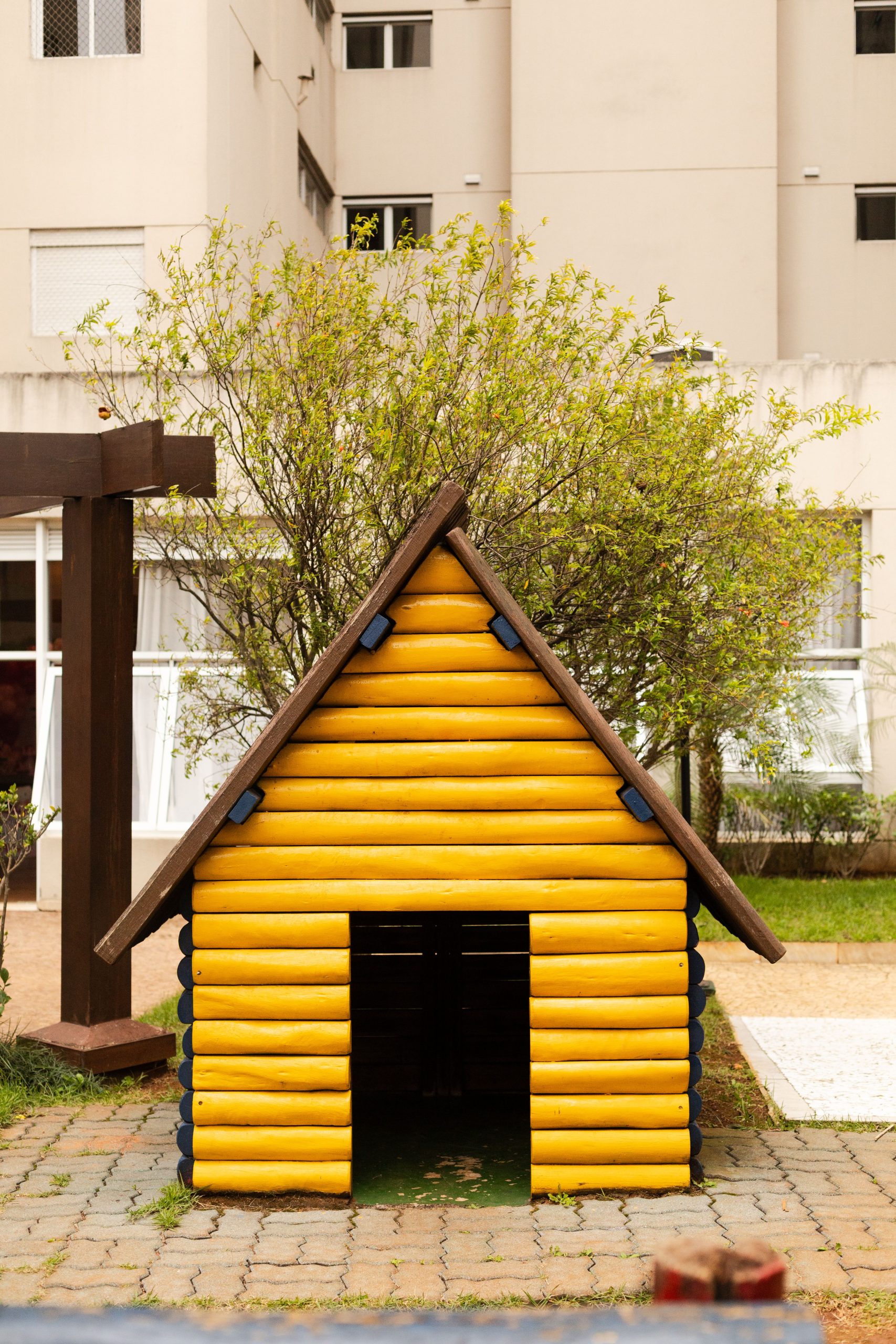 A charming yellow wooden playhouse in São Paulo against a residential backdrop.