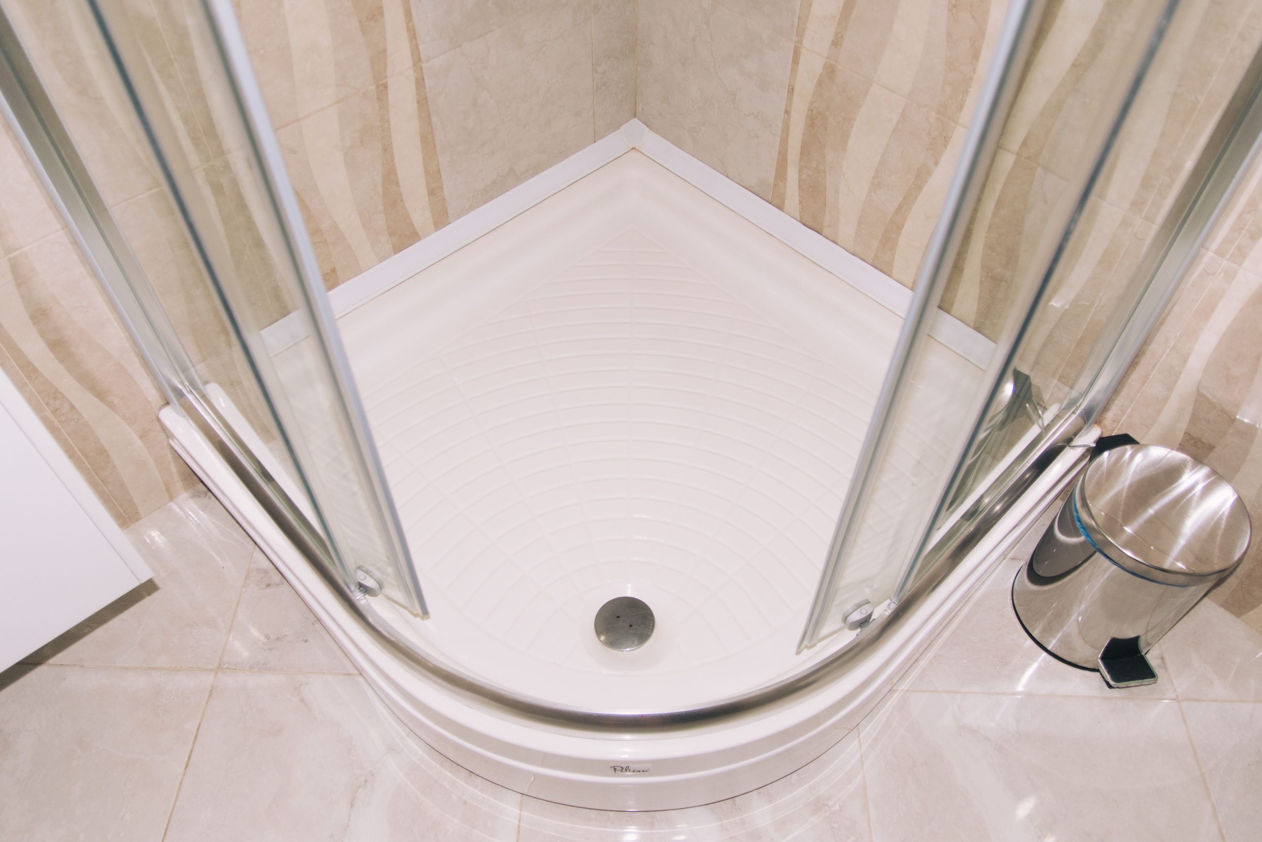 A clean, modern corner shower enclosure with glass doors in a tiled bathroom setting.