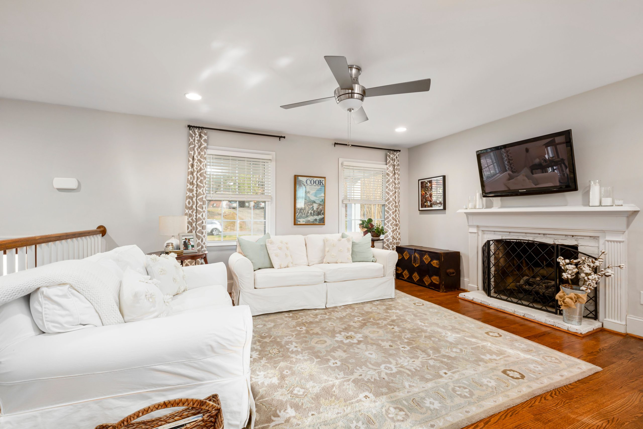 A cozy and modern living room featuring a fireplace, ceiling fan, and stylish decor.