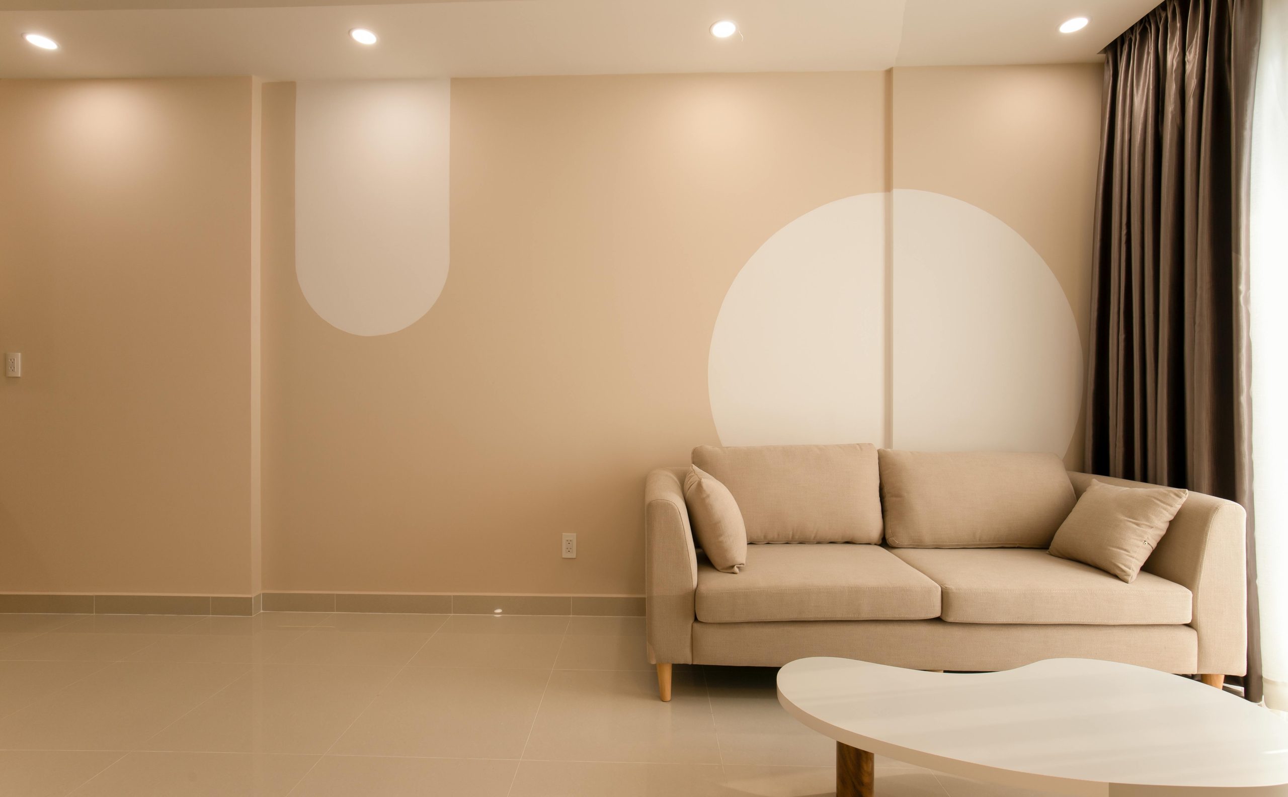 A cozy minimalist living room featuring a beige sofa, modern decor, and neutral tones for an inviting atmosphere.