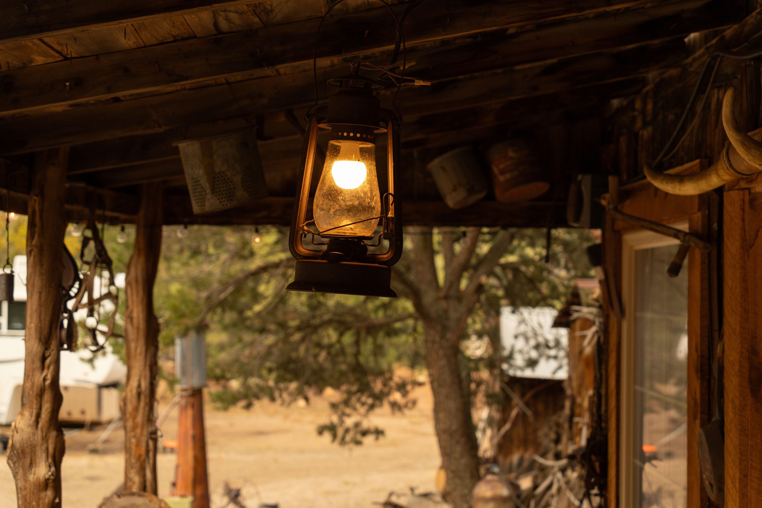 A glowing lantern hangs from a rustic wooden porch, evoking the ambiance of the wild west.