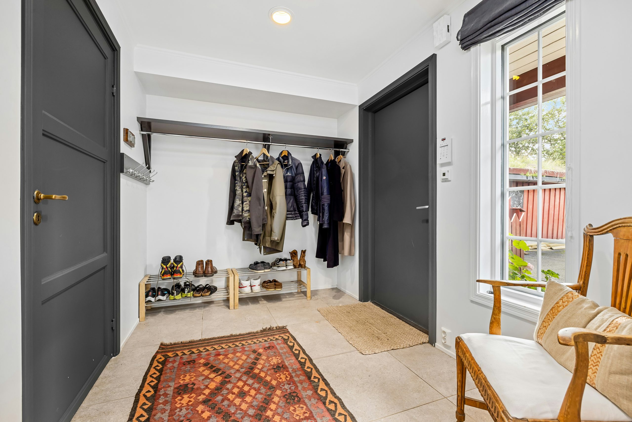 A hallway with a rug, chair, and coat rack
