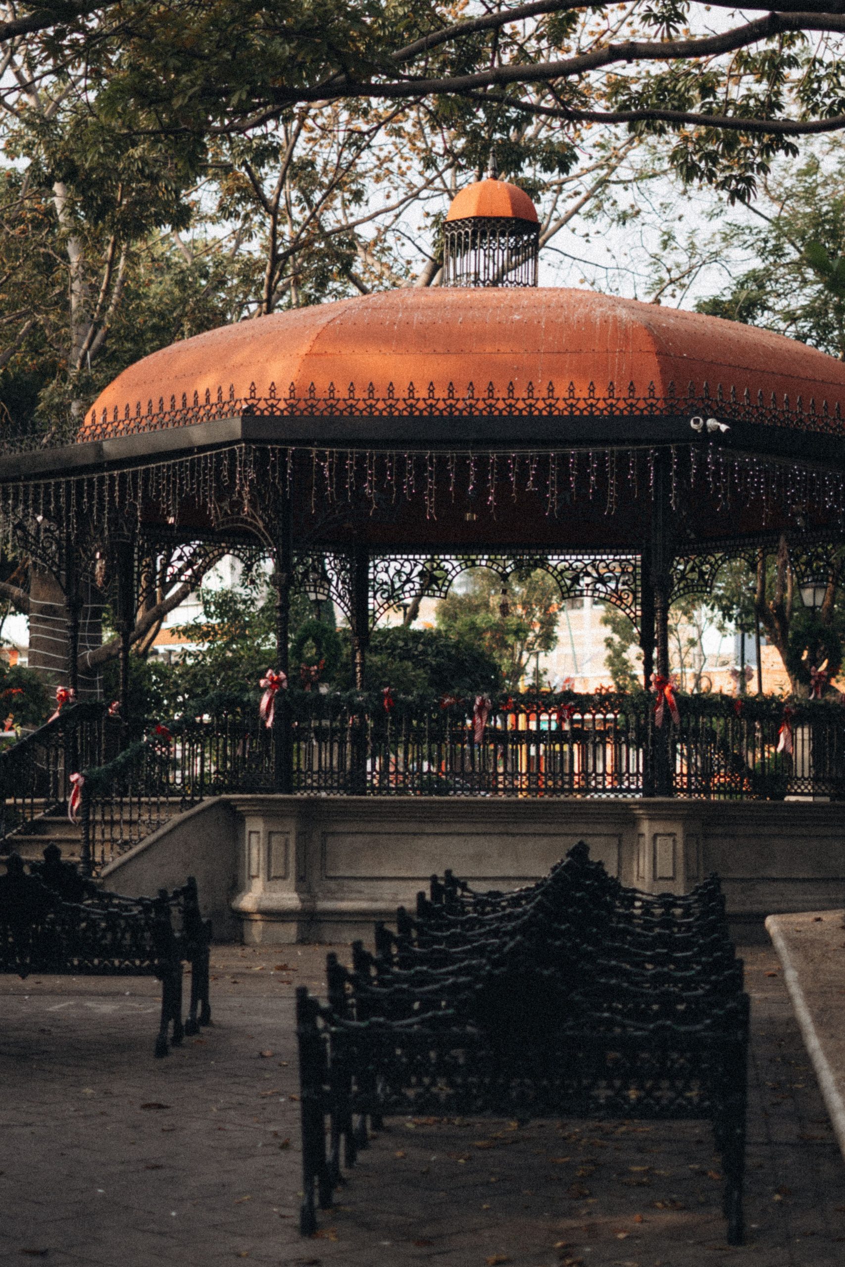 A historic outdoor gazebo surrounded by benches and trees, offering a peaceful retreat.