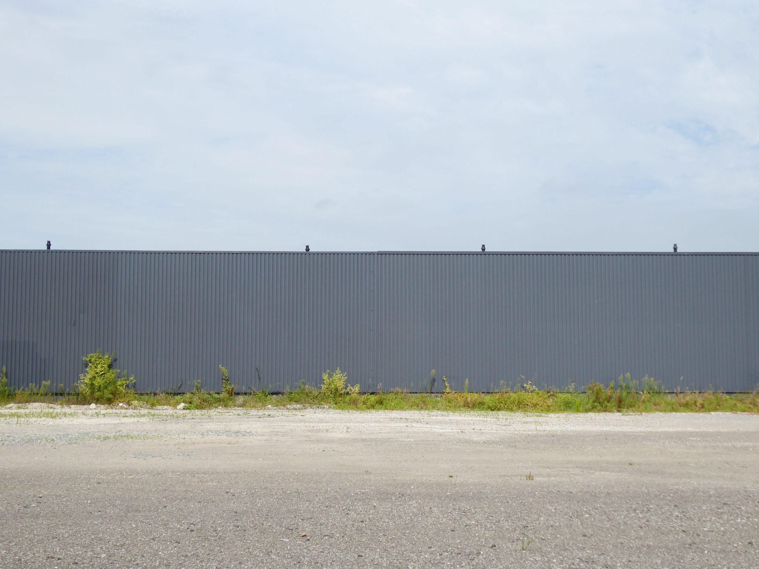 A long metal fence stretches across an empty outdoor area, under a cloudy sky.