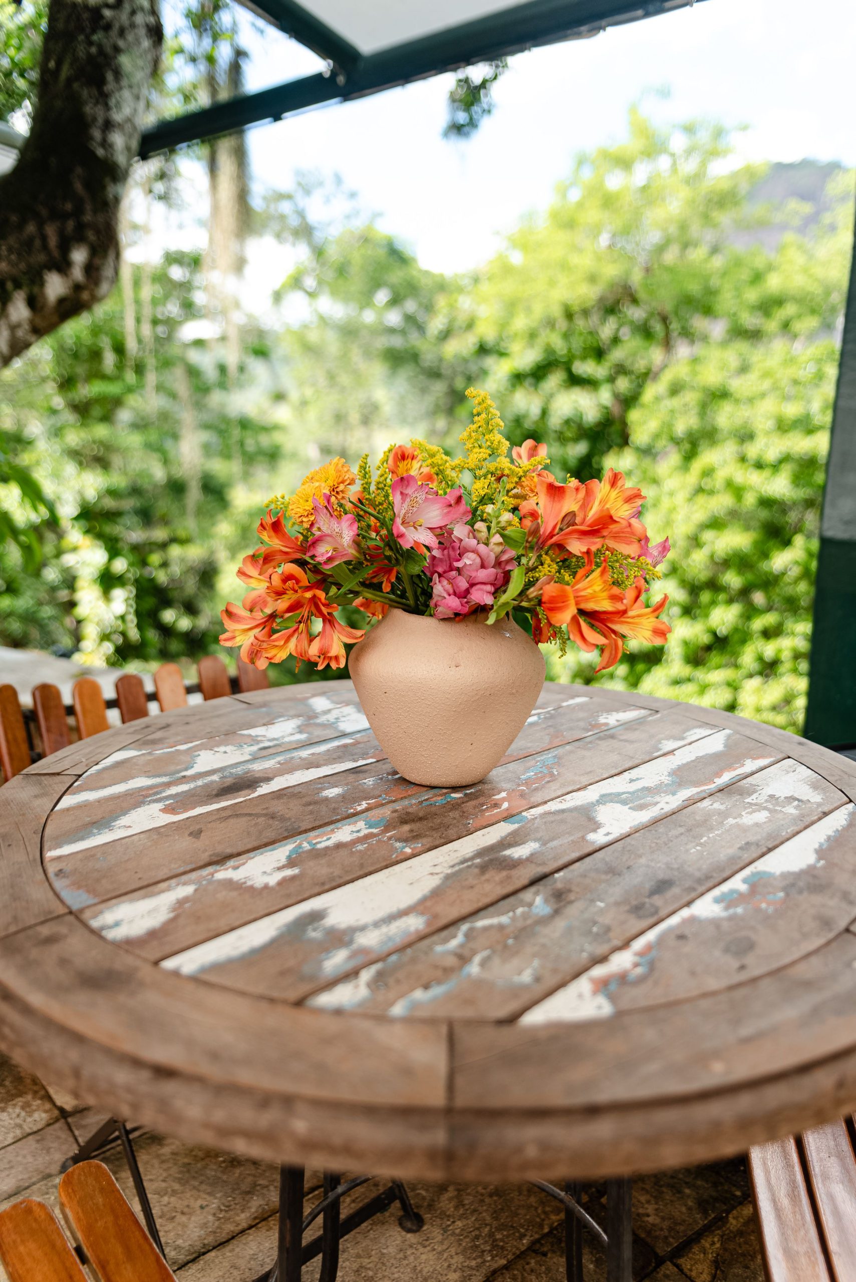 A rustic wooden table with a colorful flower arrangement, perfect for summer patios.