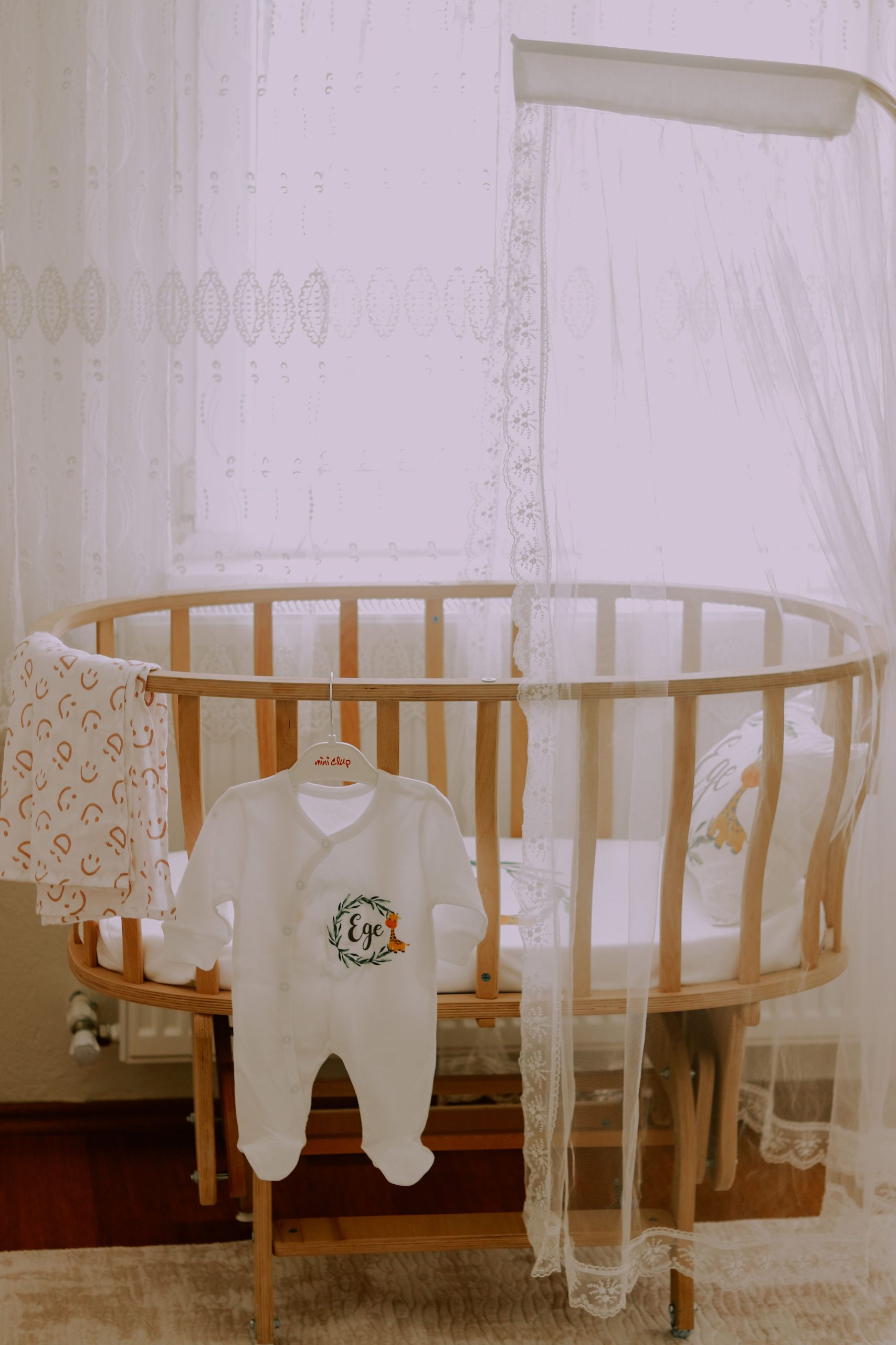 A serene baby room featuring a wooden crib and a cute baby outfit.