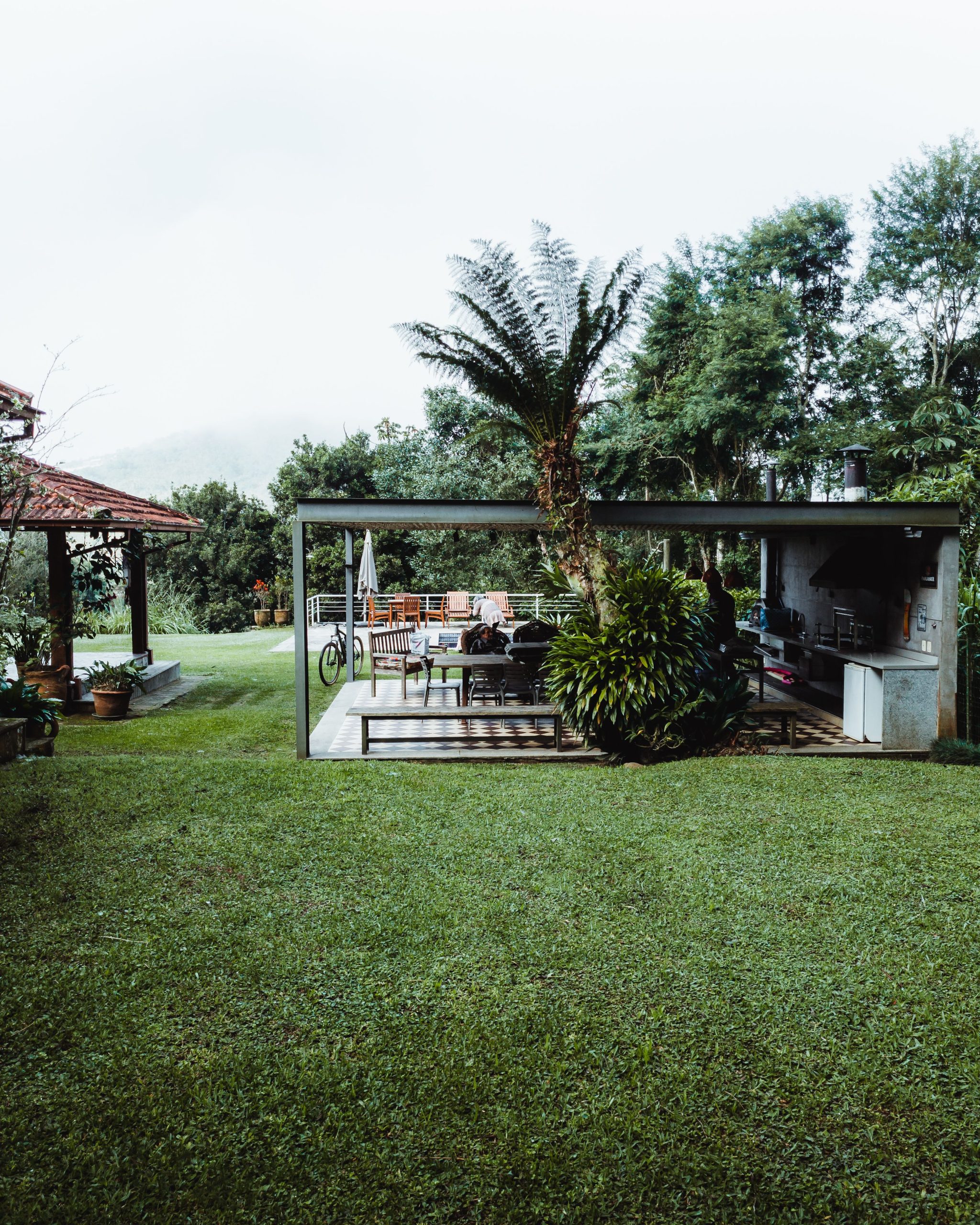 A serene backyard featuring a modern gazebo surrounded by vibrant plants and outdoor furniture.