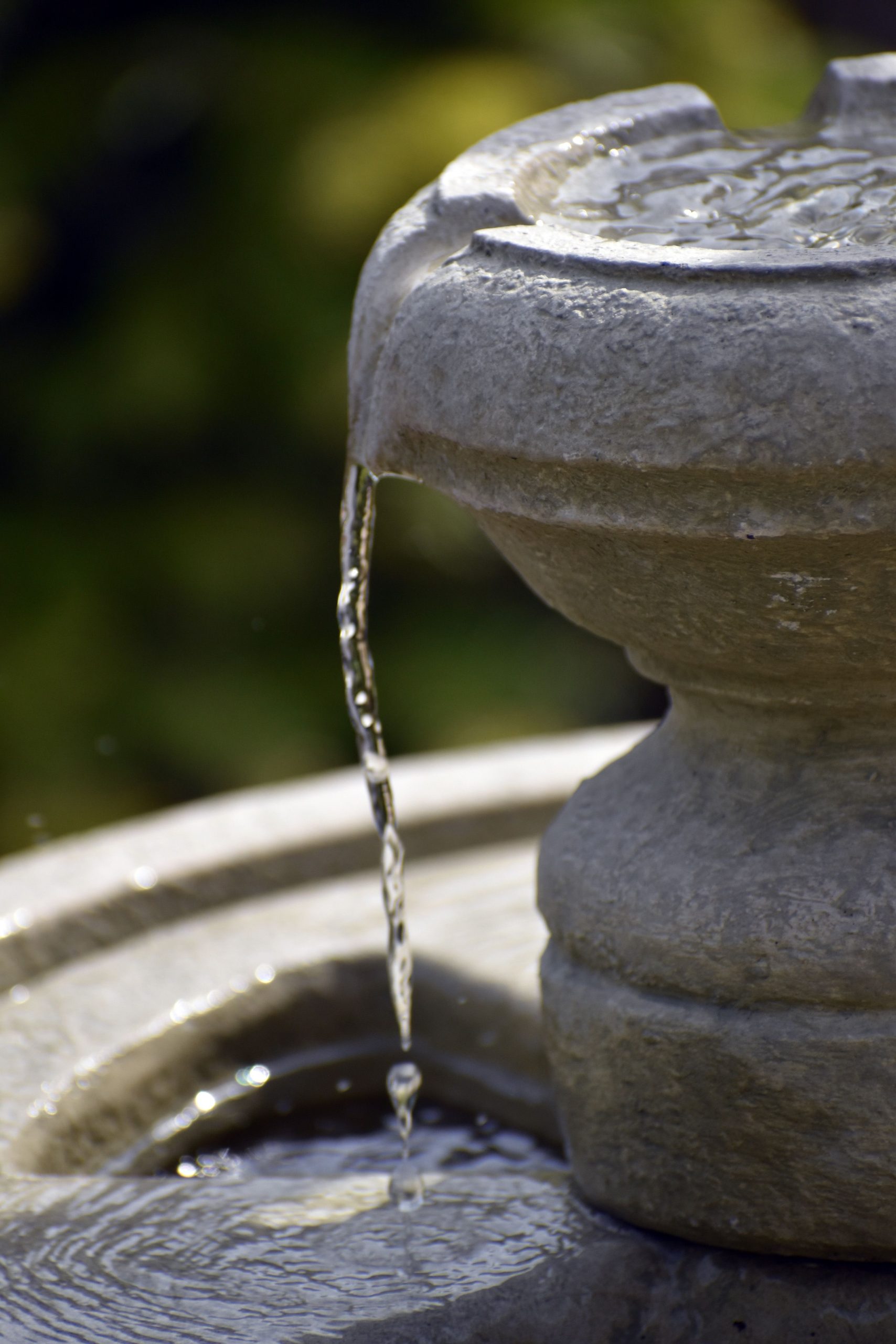A serene close-up of a stone water fountain with flowing water outdoors.