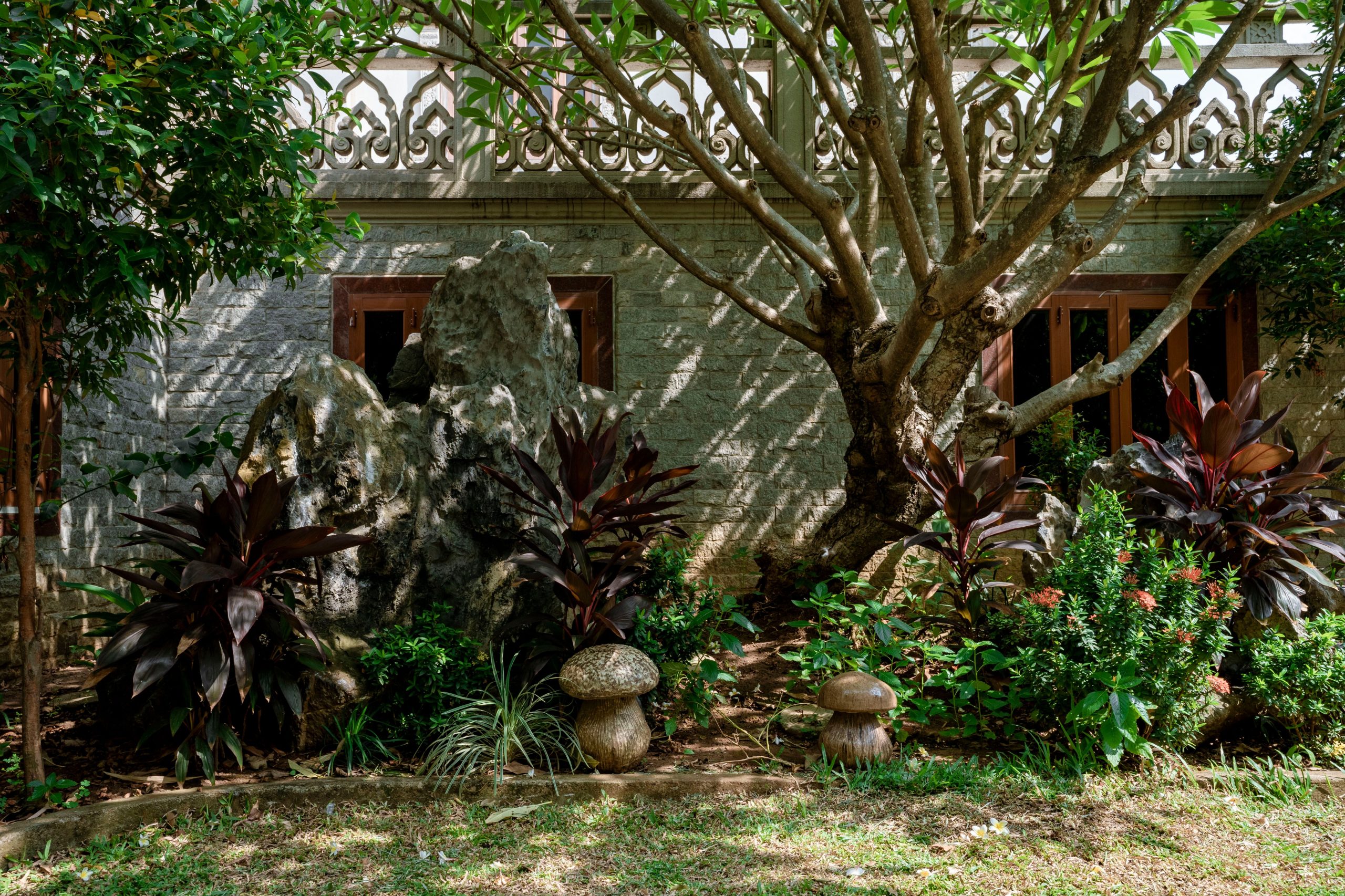 A serene garden with a variety of lush plants and stones in front of a house.