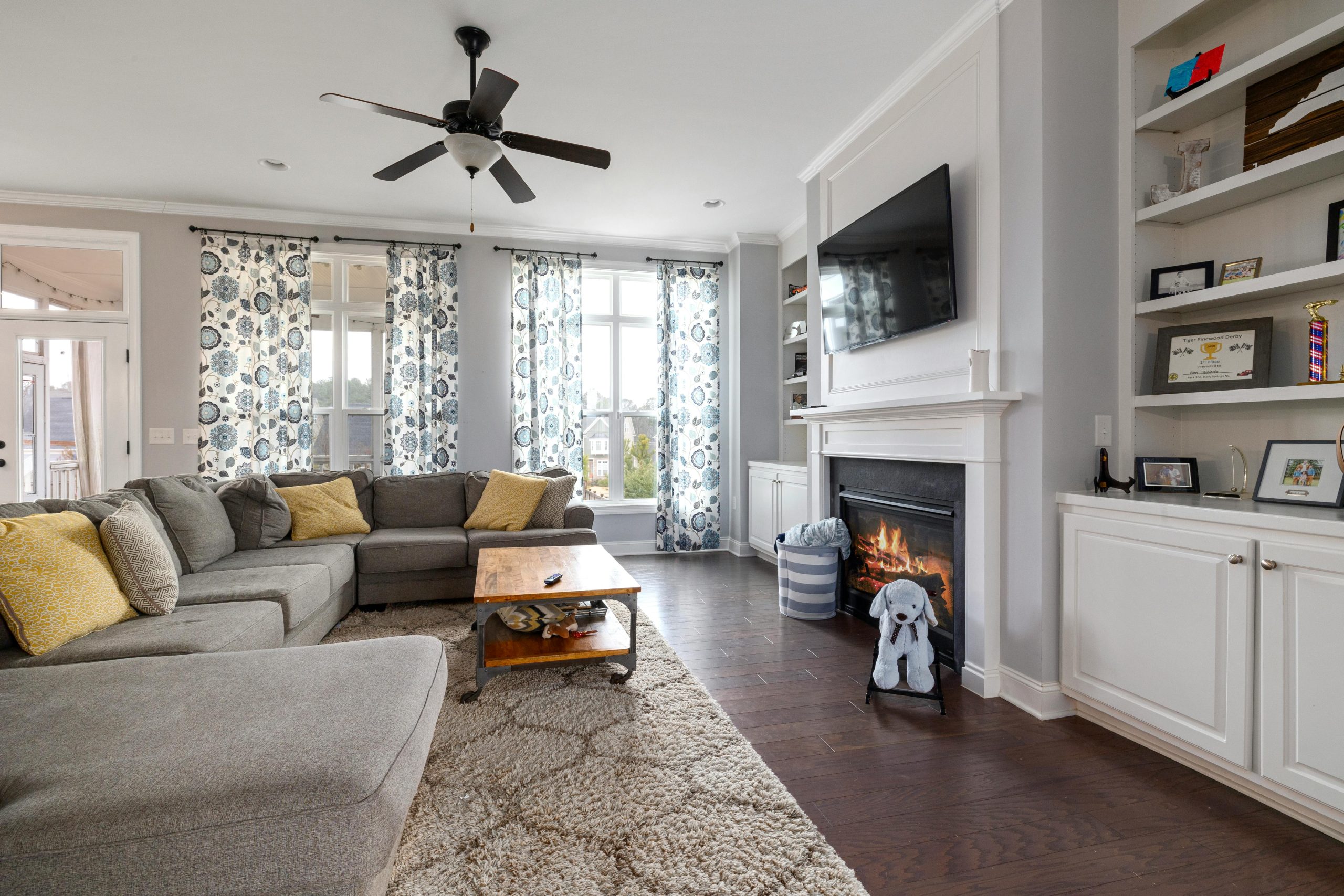 A spacious living room featuring a cozy fireplace, modern sofa, and elegant decor with natural light.