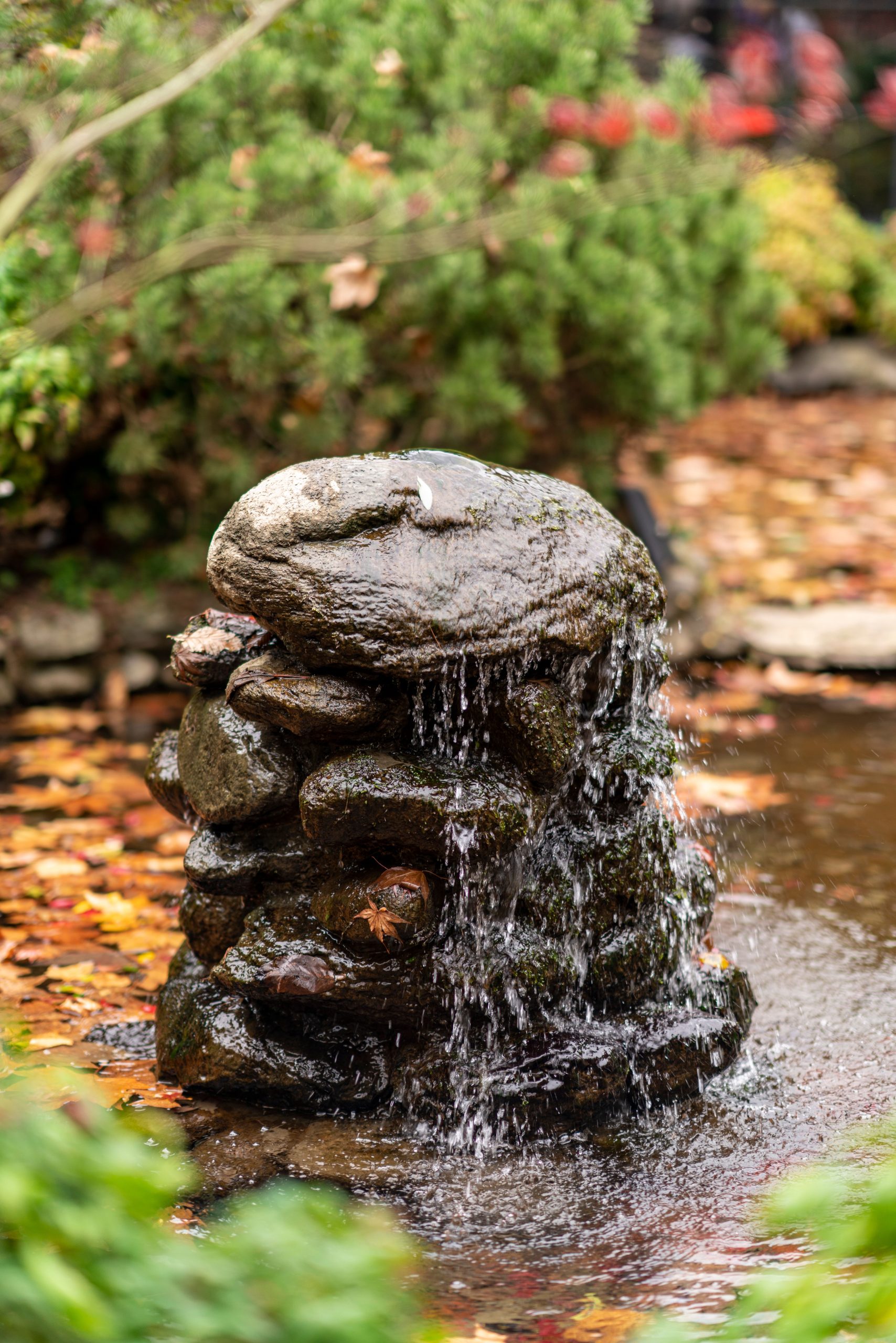 A tranquil rock fountain with cascading water in a serene garden setting.
