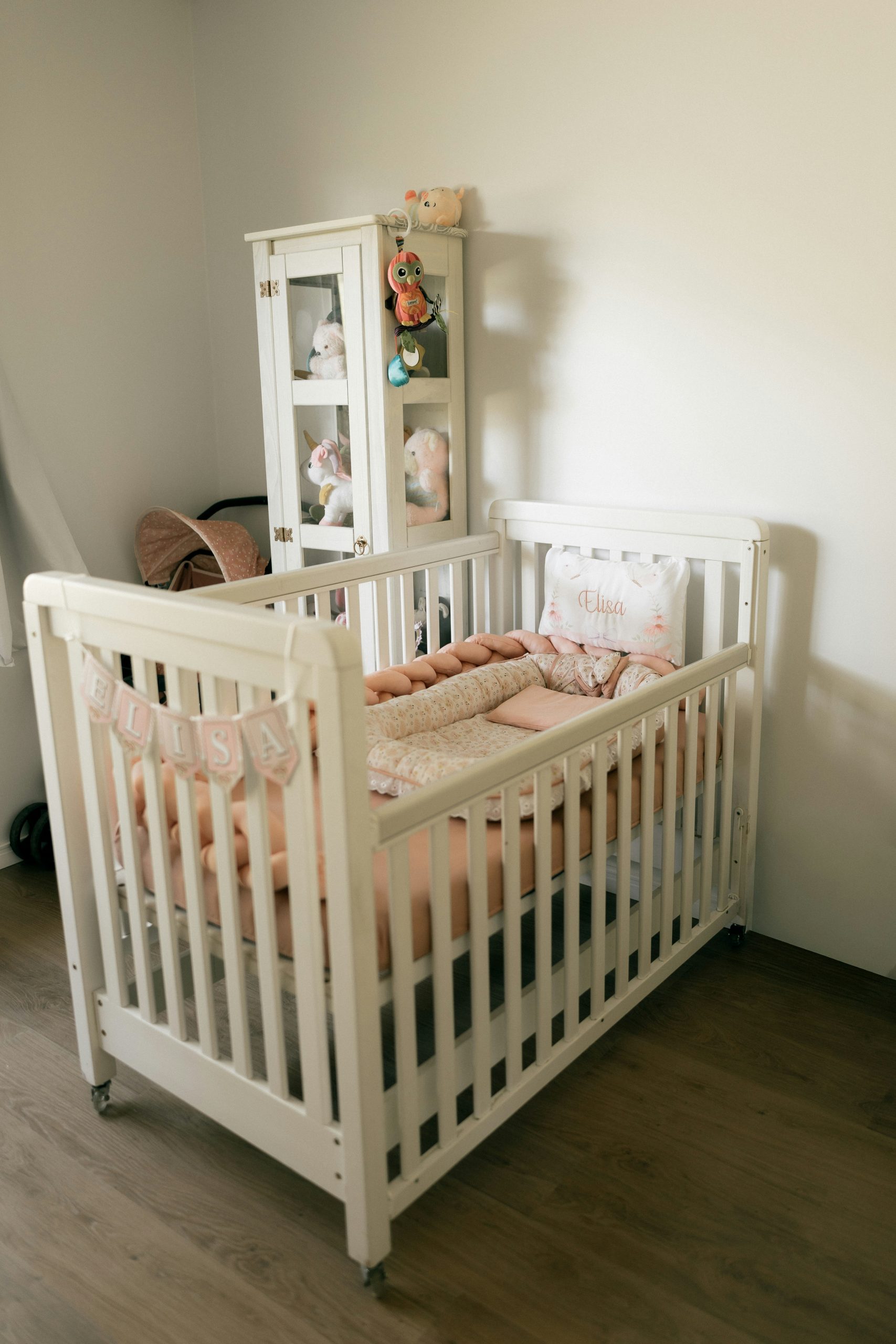 A white crib with pink bedding in a room