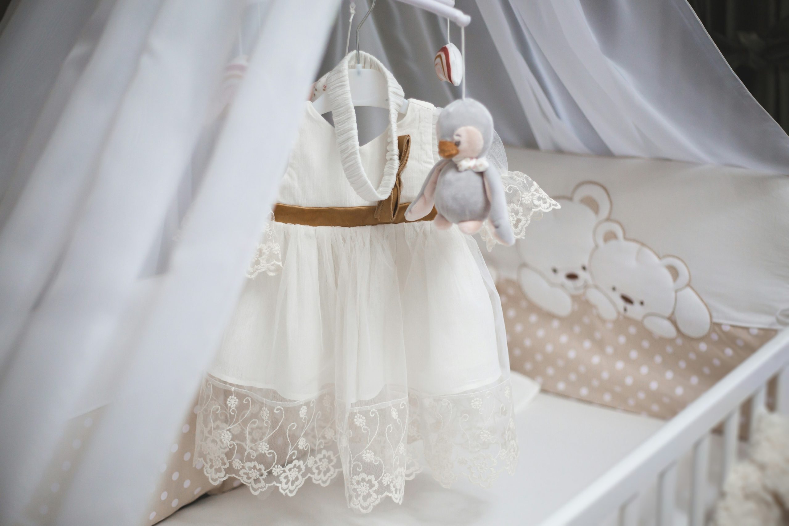 Baby girl dress hanging over cradle.