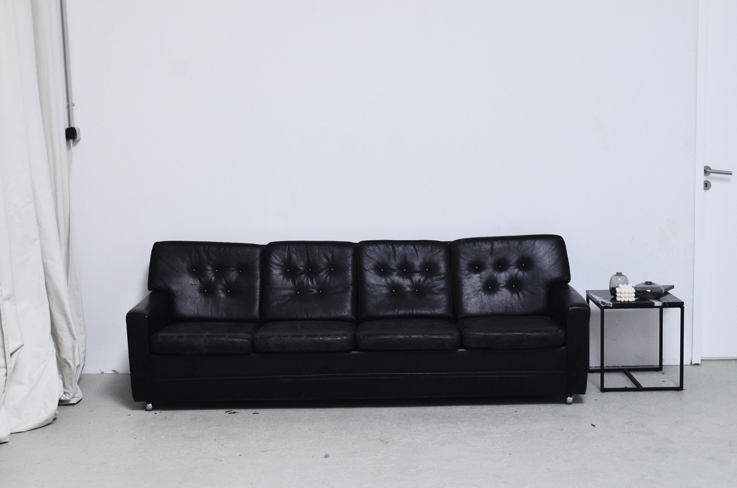 Black and white of leather couch near rectangular shaped table with decorative candle and vases in living room