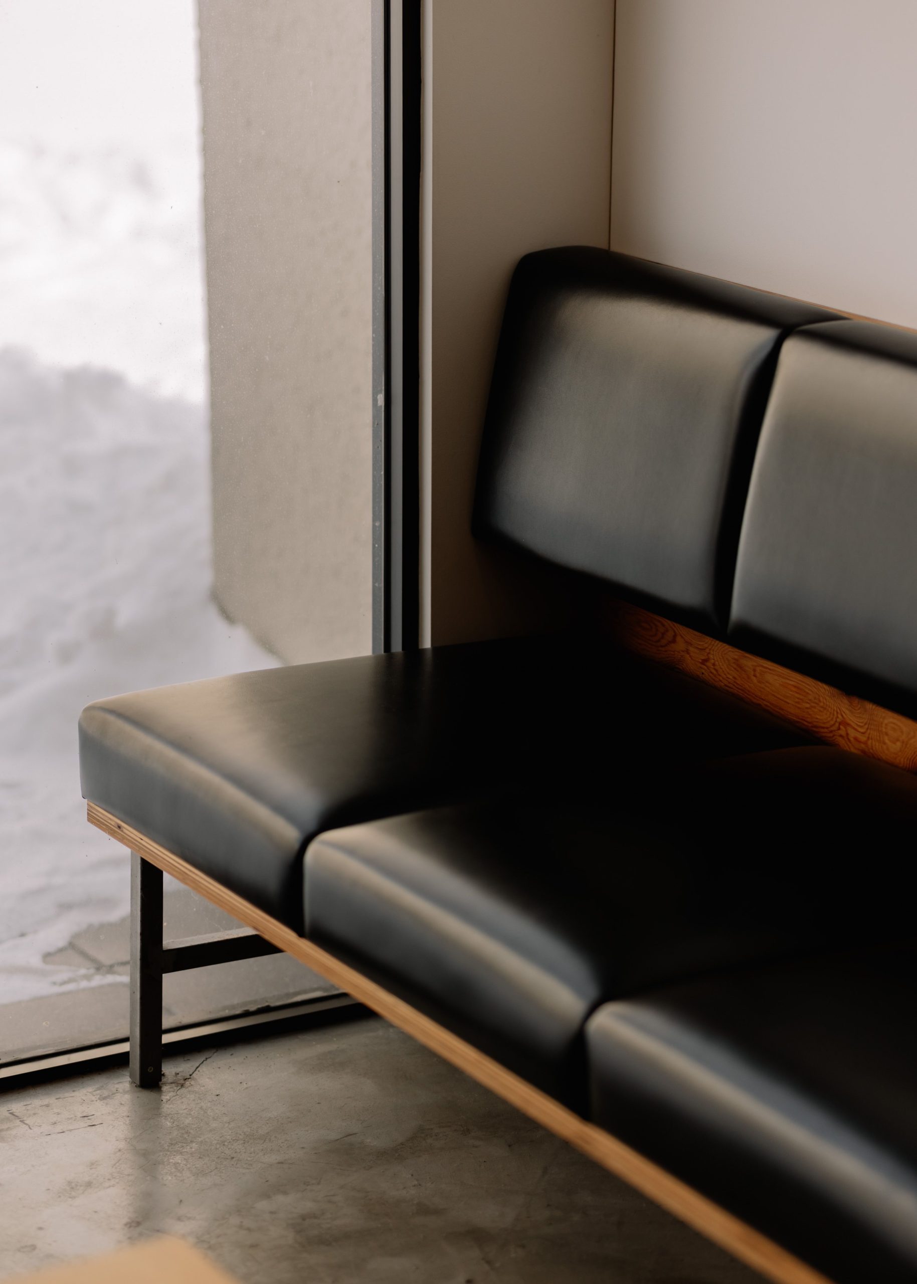 Black leather couch in a sunlit minimalist space in Hokkaido, Japan.