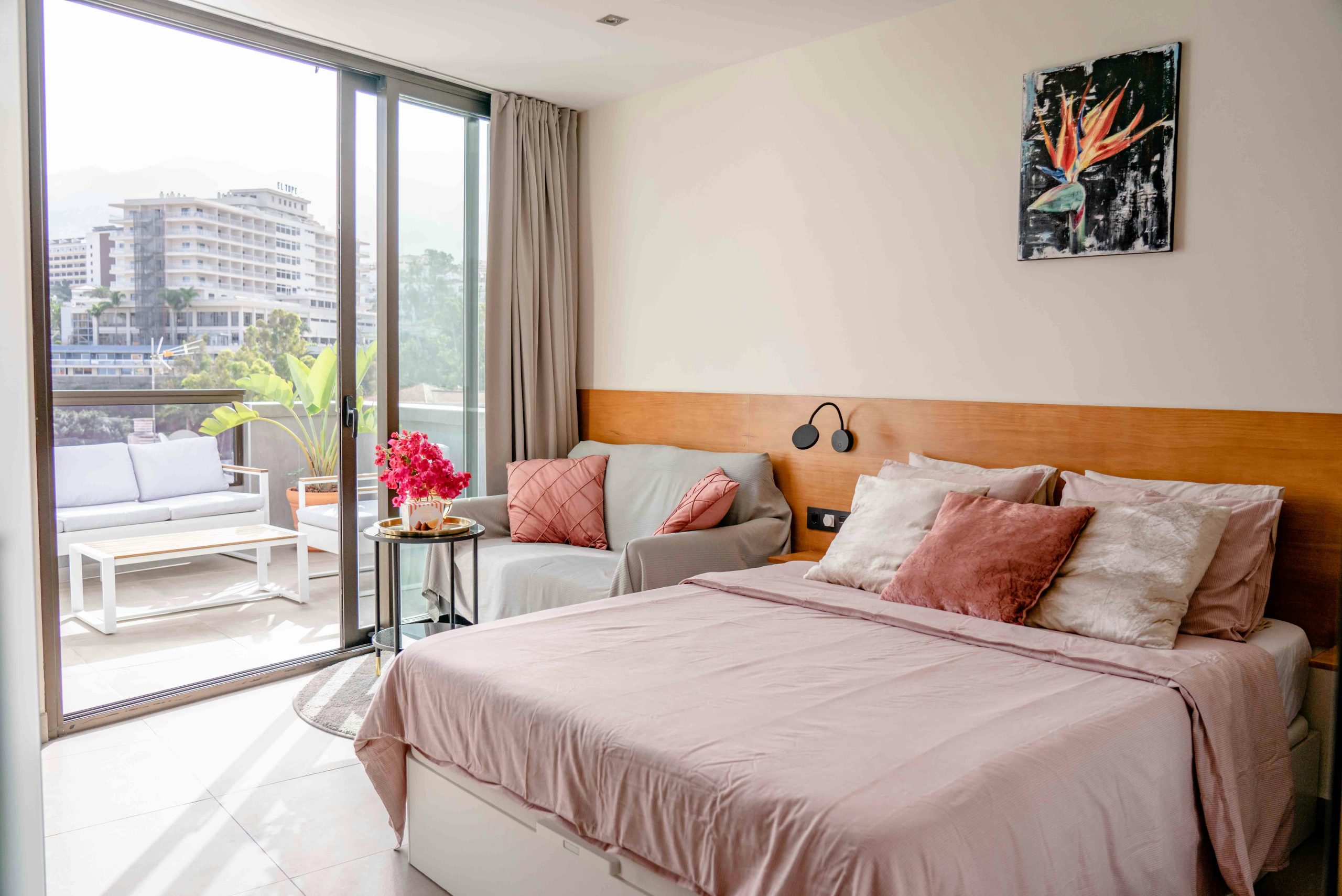 Bright and cozy modern bedroom with city view and furnished balcony.