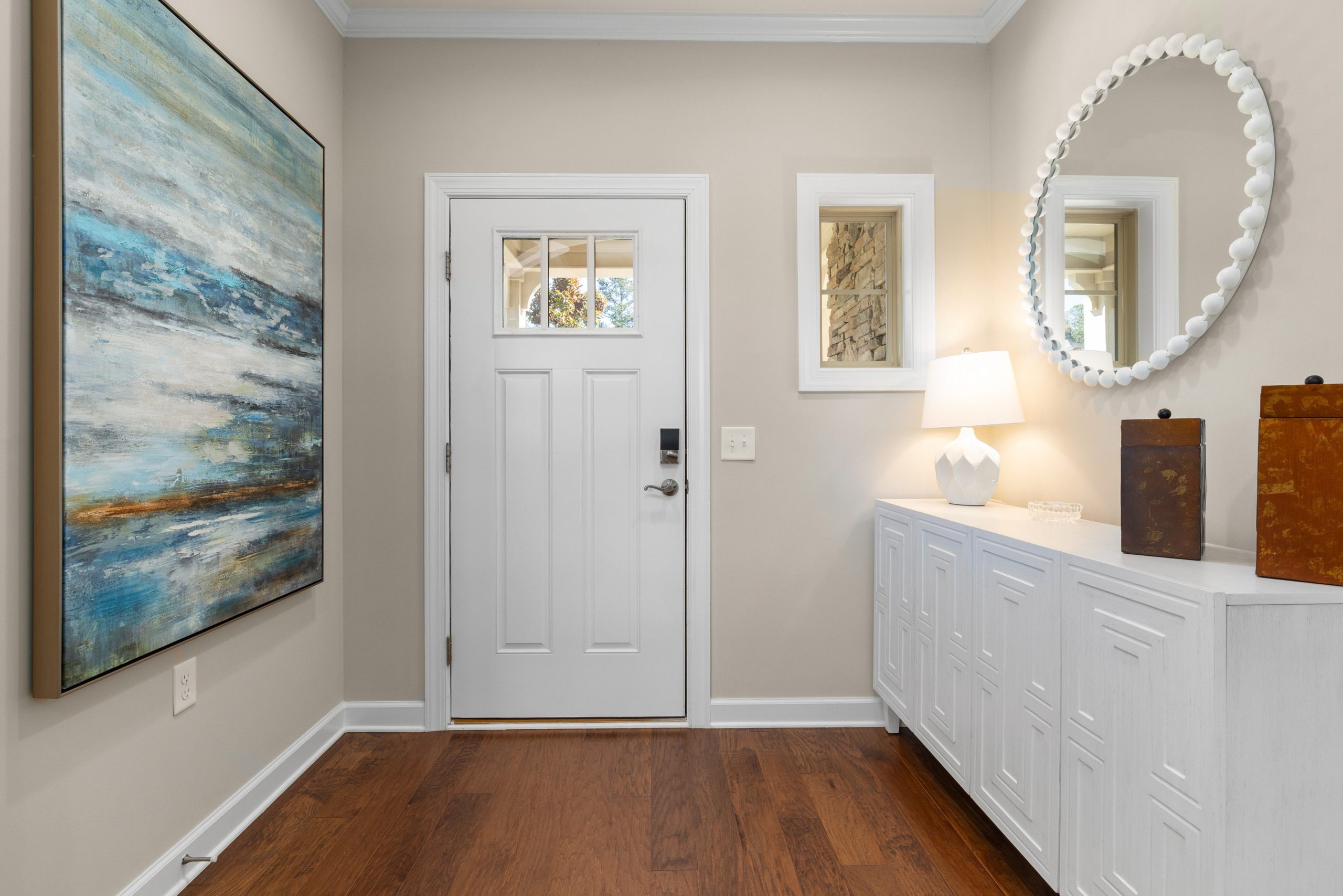 Bright and modern entryway featuring abstract art, a white door, and elegant decor. Ideal for contemporary living spaces.