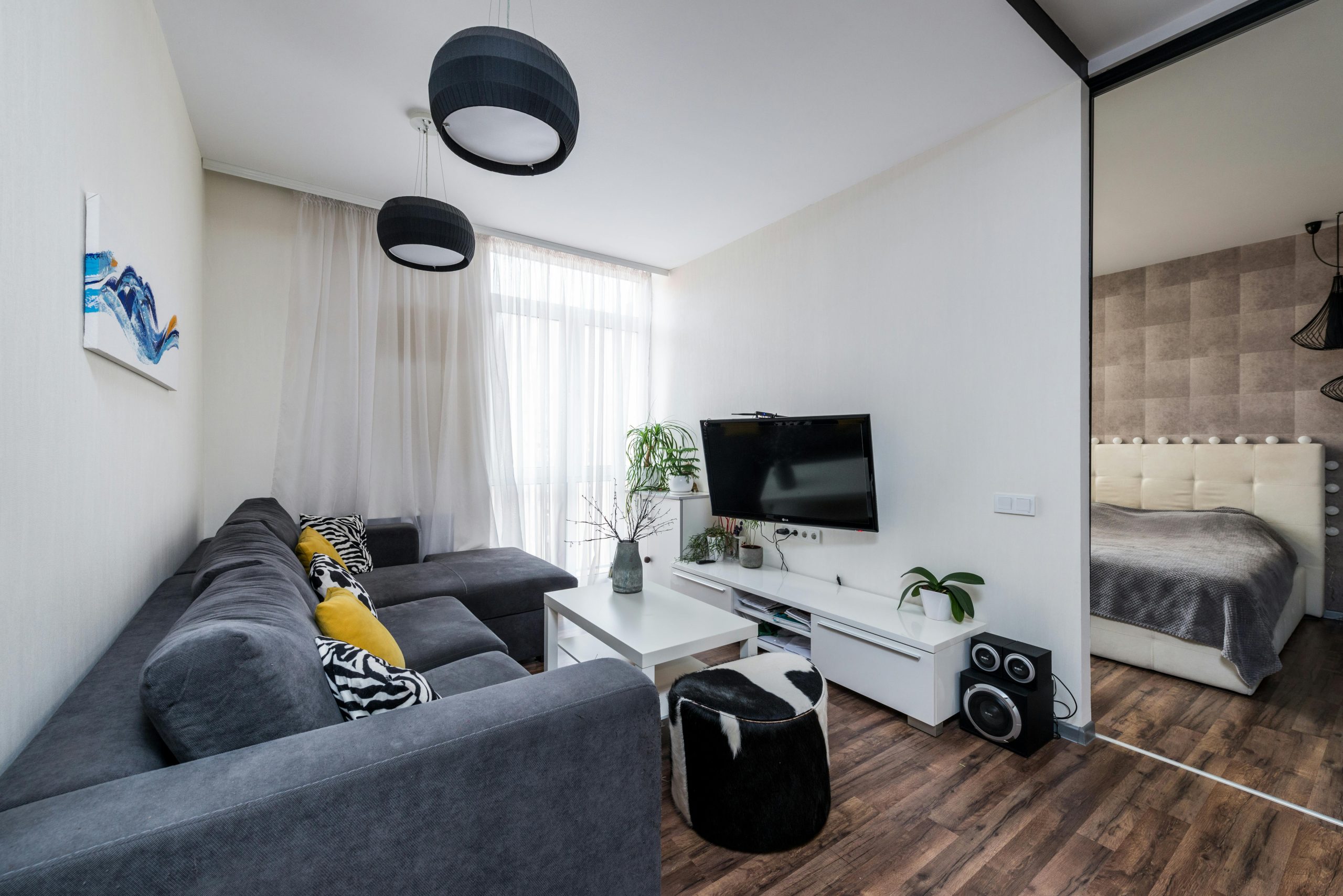 Bright living room interior with modern furnishings and cozy atmosphere, featuring a gray sofa and indoor plants.