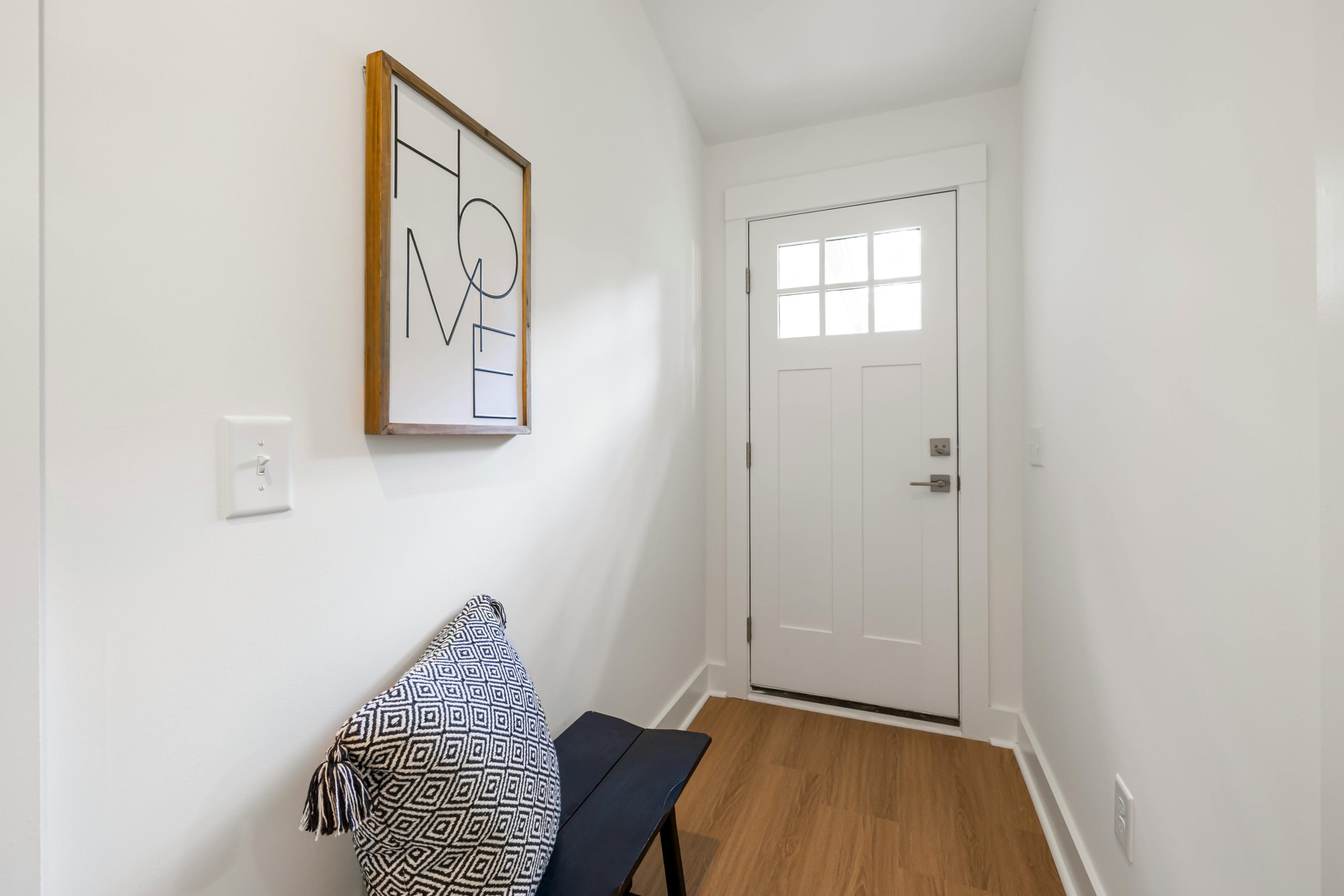 Bright minimalist hallway with a bench and decor, showcasing contemporary design.