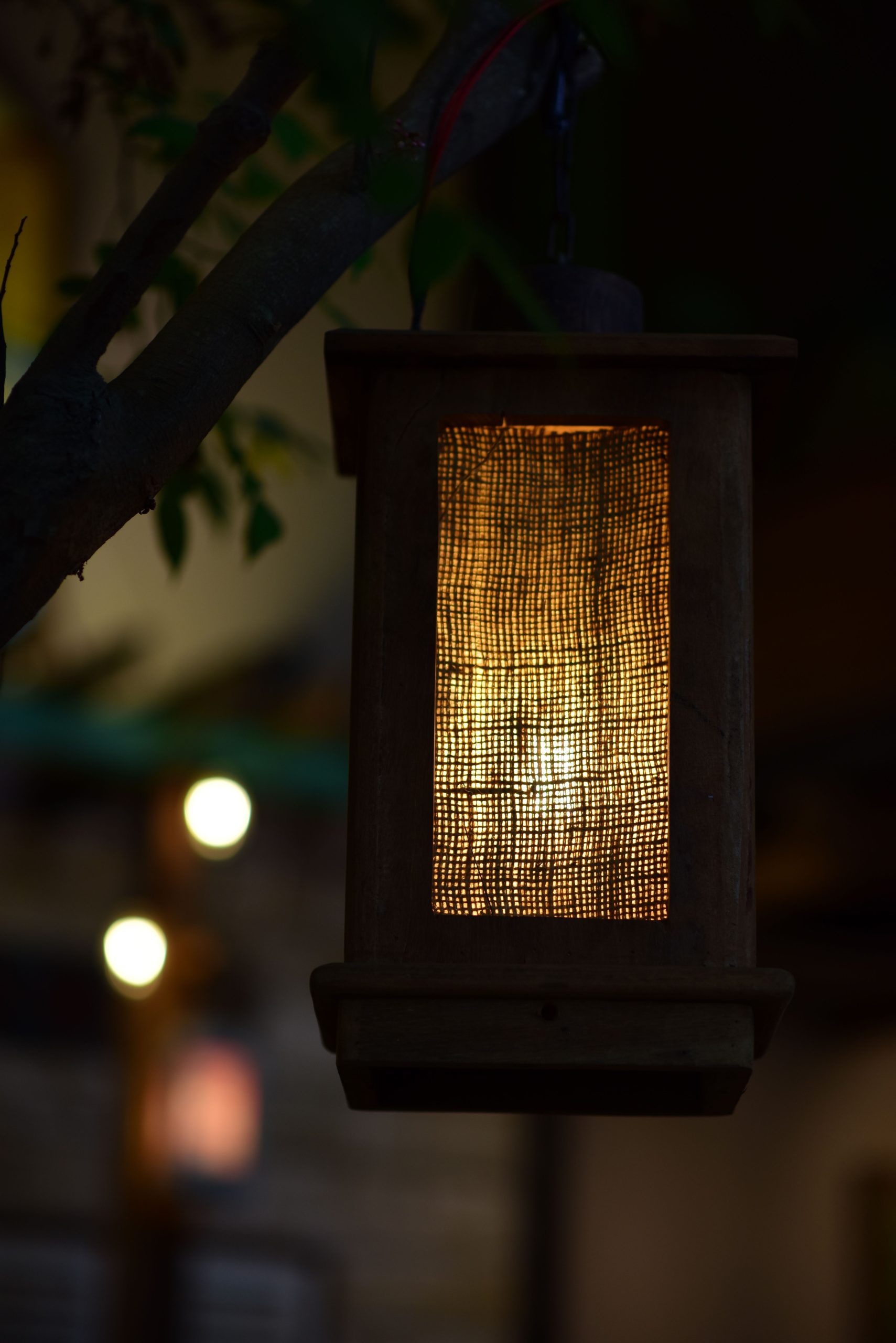 Close-up of a rustic wooden lantern glowing warmly against a blurred night background.