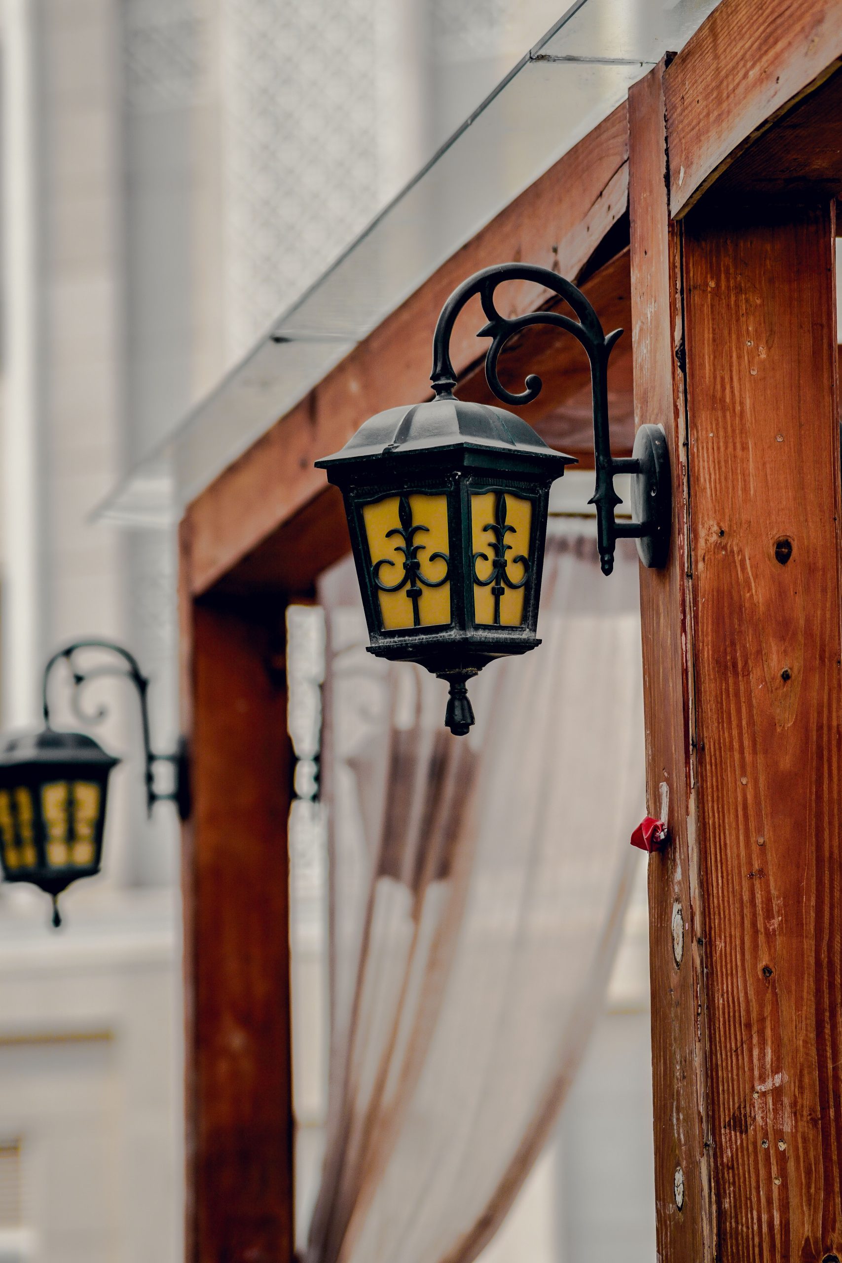 Close-up of vintage lanterns mounted on a wooden structure against a blurred architectural background.