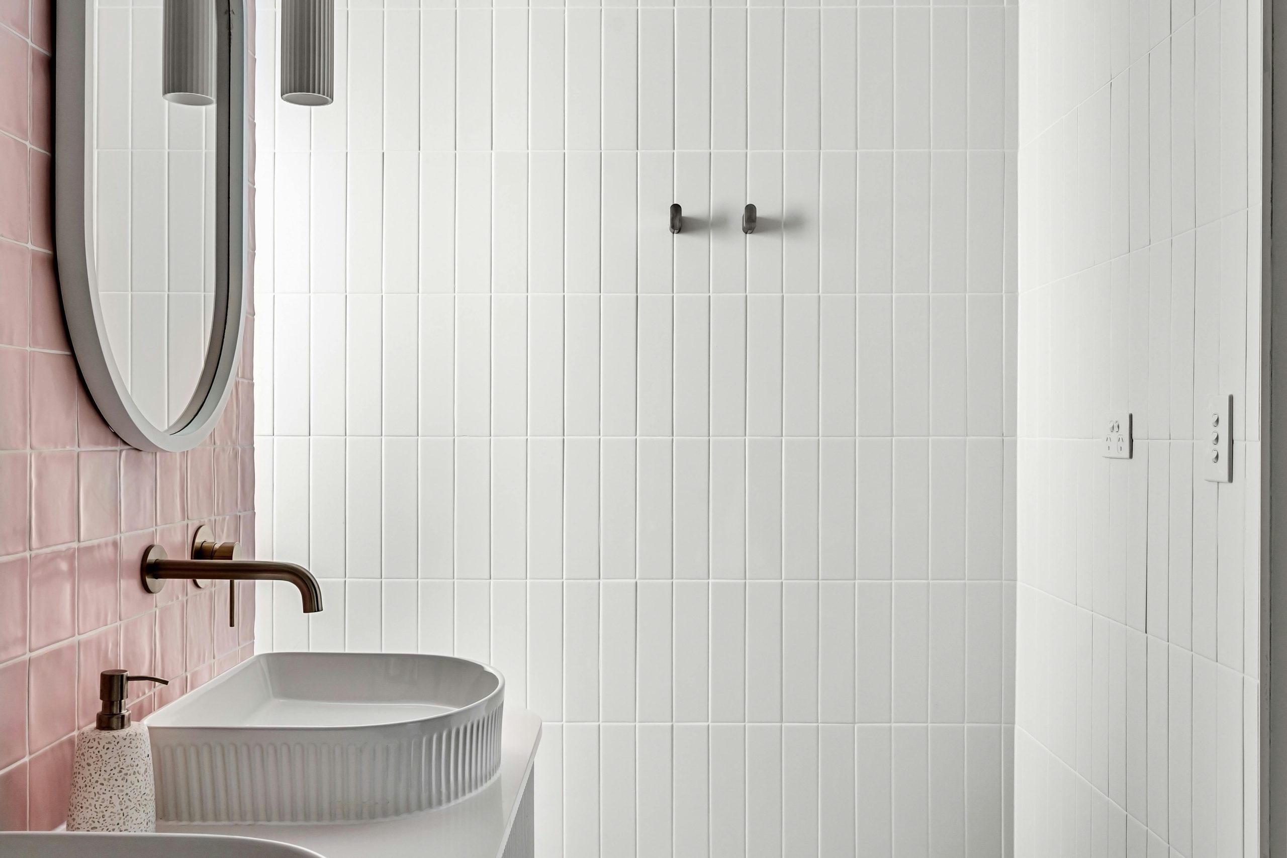 Contemporary bathroom featuring minimalist design with pink and white tiles and a sleek faucet.