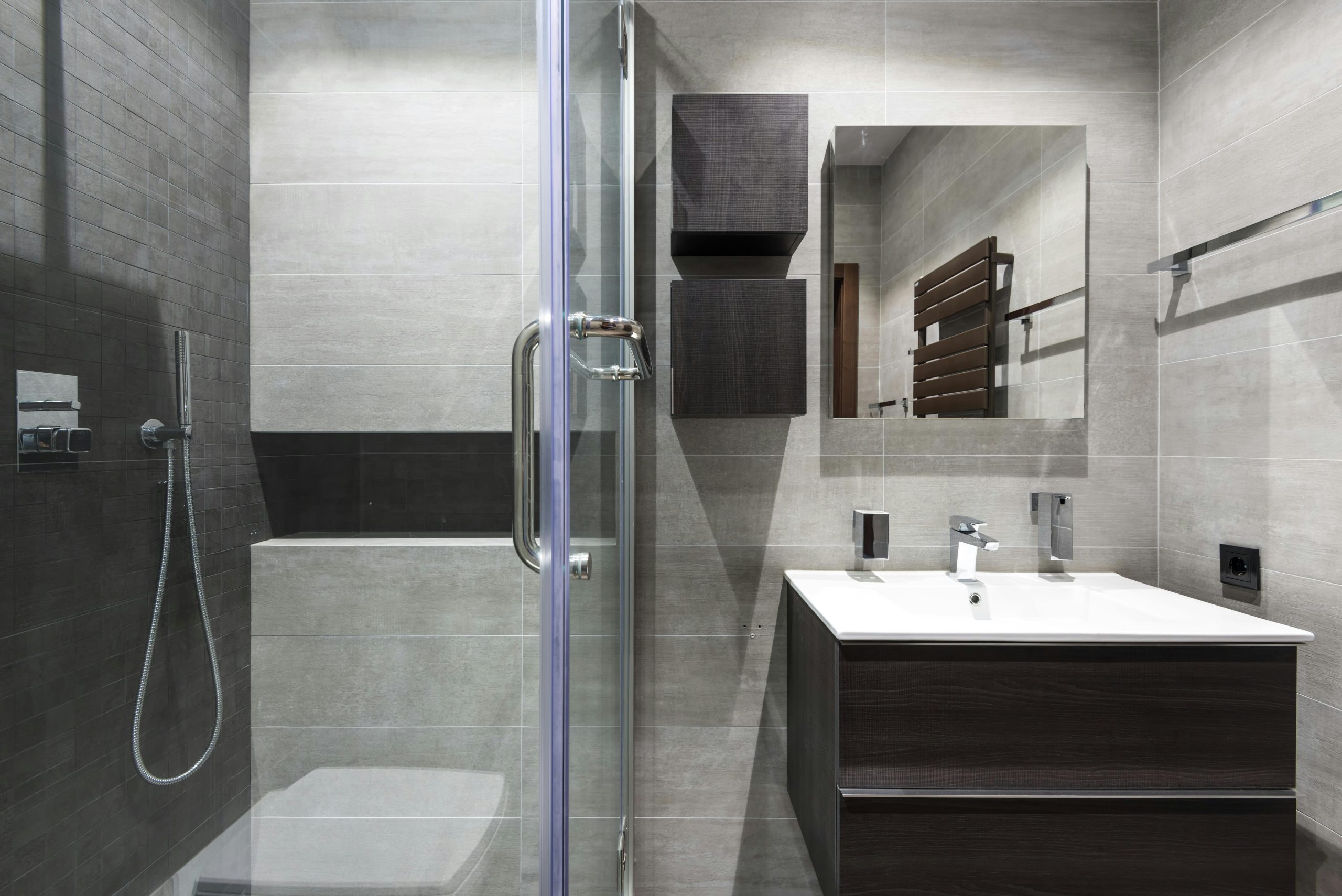 Contemporary bathroom interior in grayscale, featuring a shower, mirror, and minimalist decor.