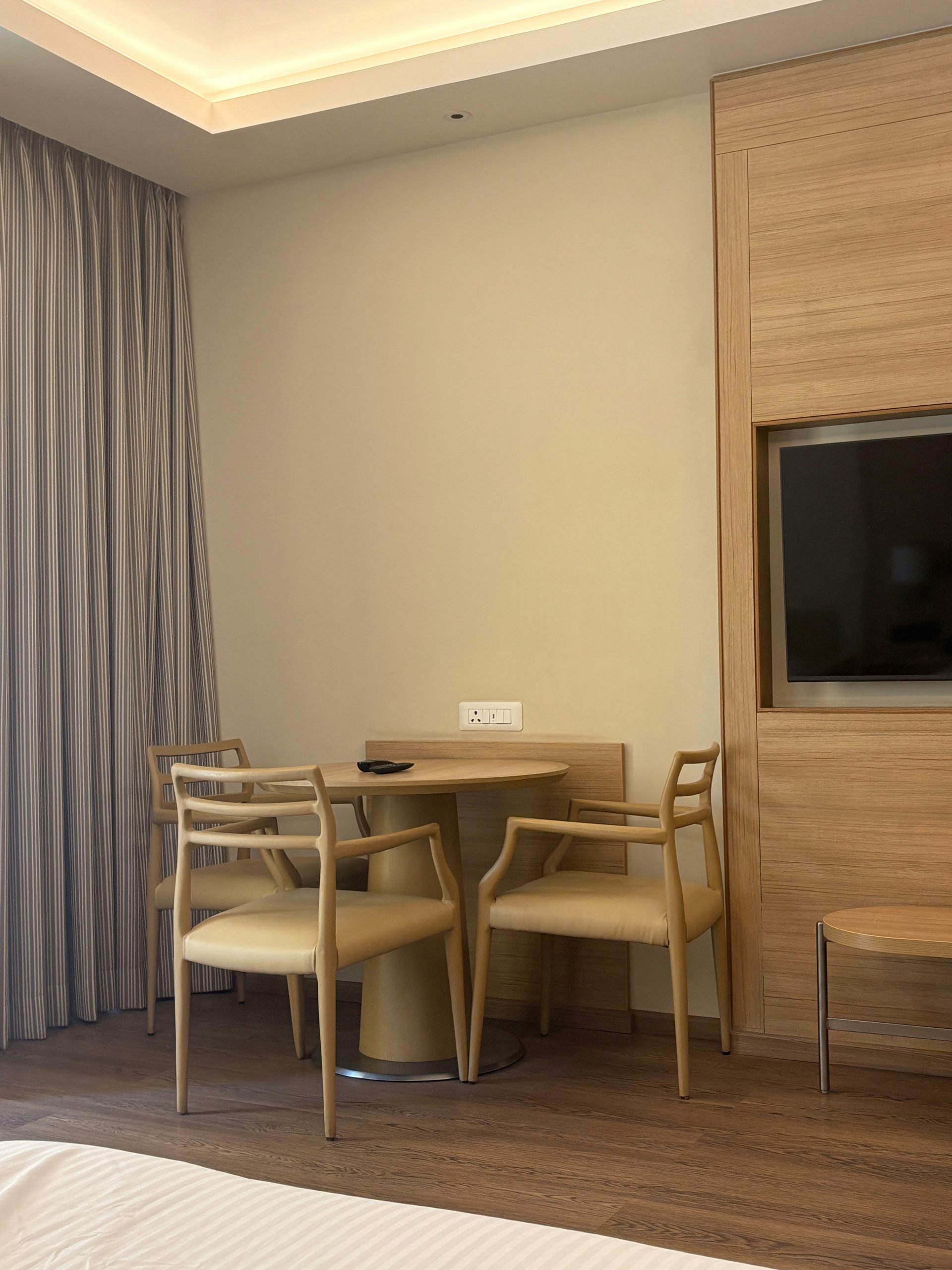 Contemporary hotel room with a small dining area and tv.