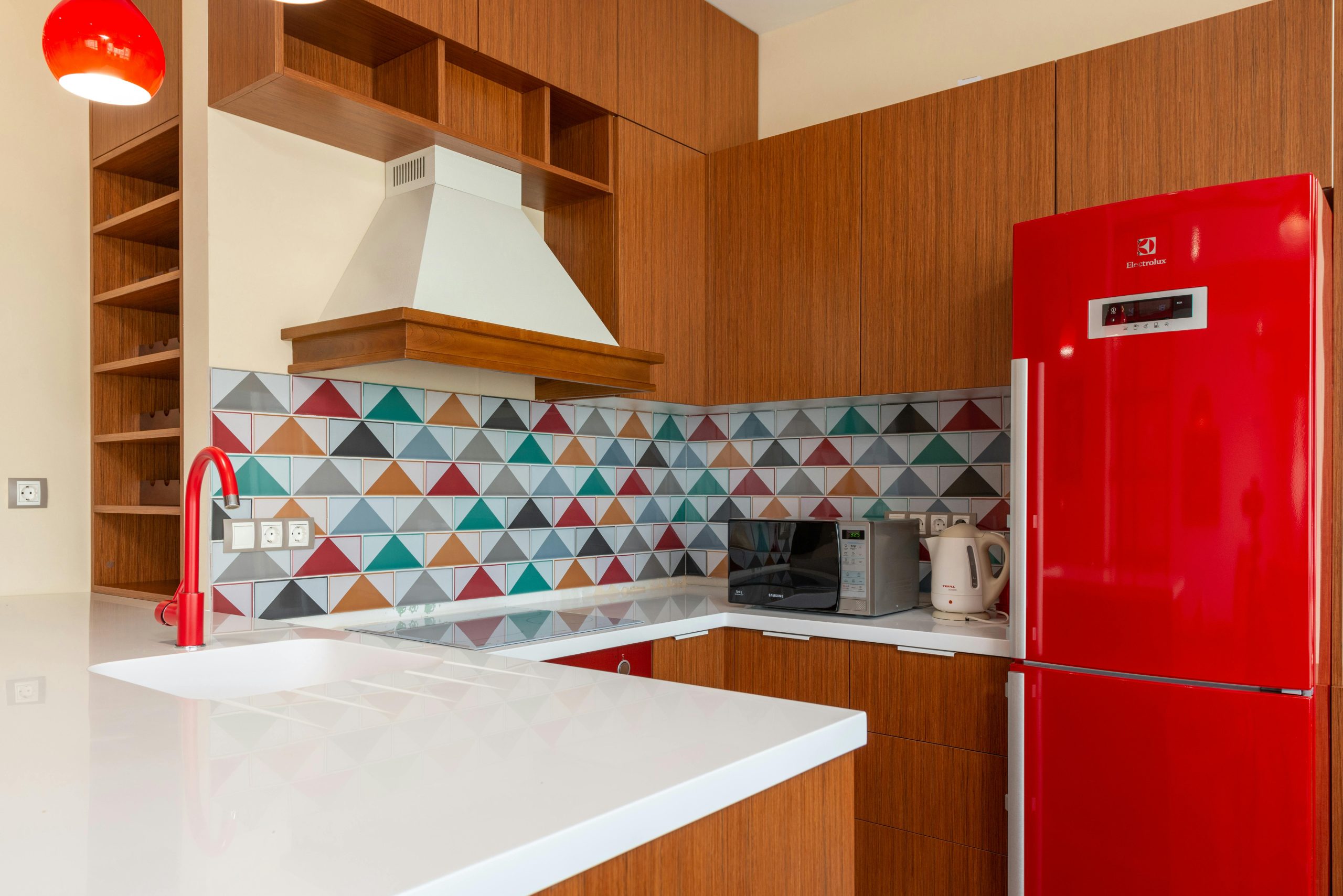 Contemporary kitchen design featuring colorful geometric tiles and red appliances.