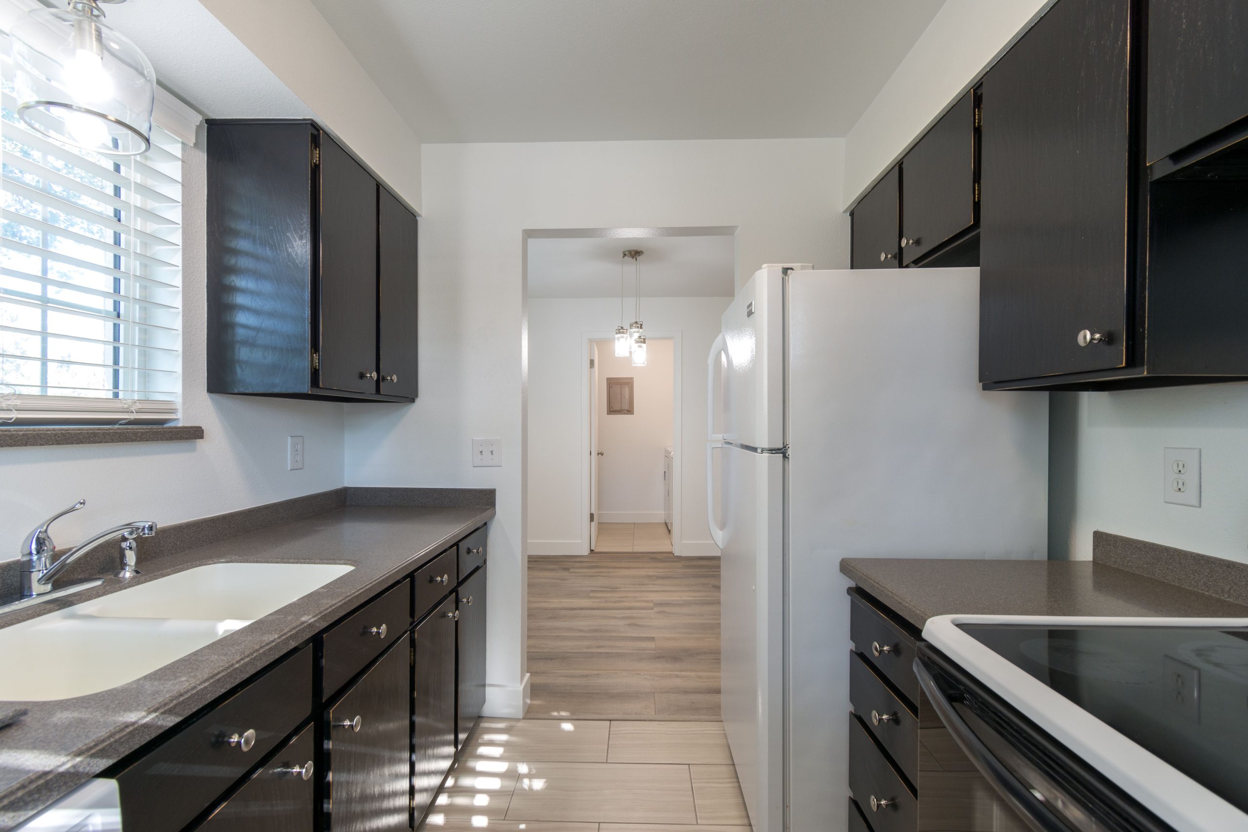 Contemporary kitchen design featuring dark cabinets, countertops, and white appliances for a sleek look.