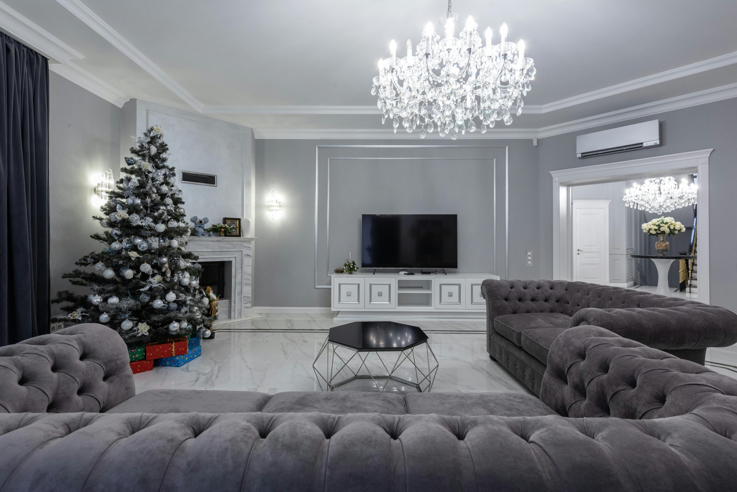 Contemporary spacious living room with glowing massive chandelier and modern TV near geometrical table