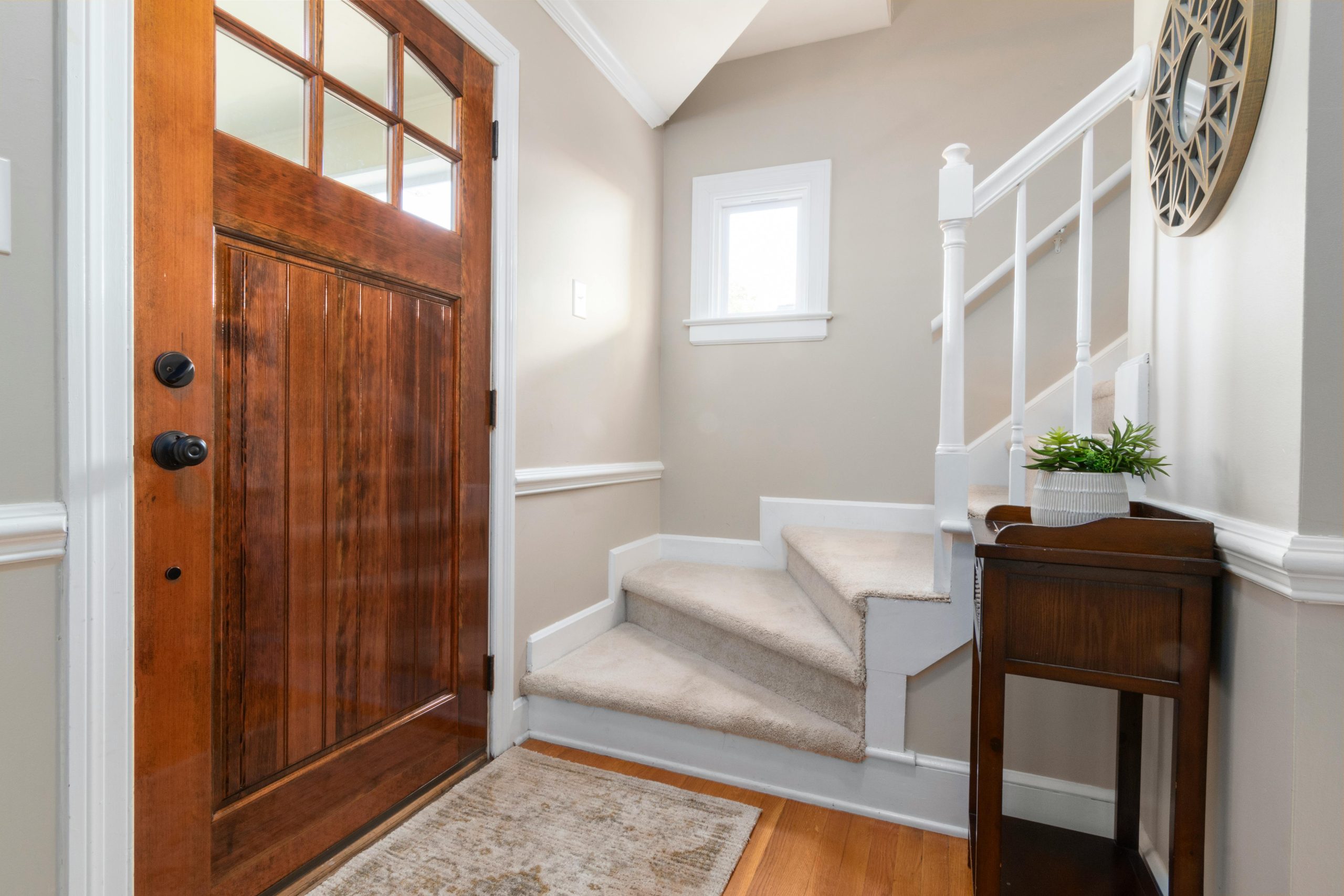 Cozy and modern home entrance featuring a wooden door and carpeted staircase.