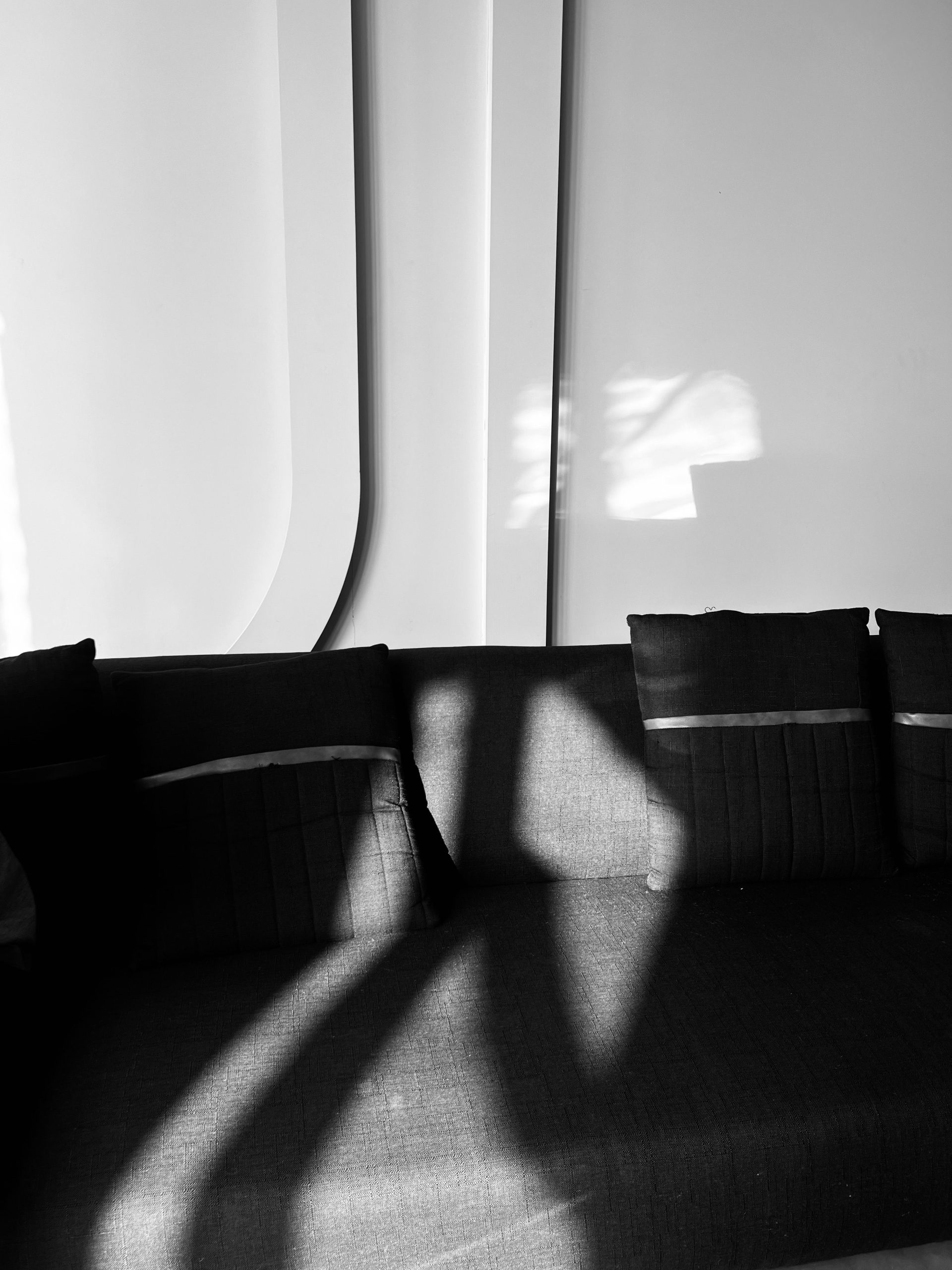 Elegant black and white interior with sunlight casting dramatic shadows on a sofa in Pakistan.