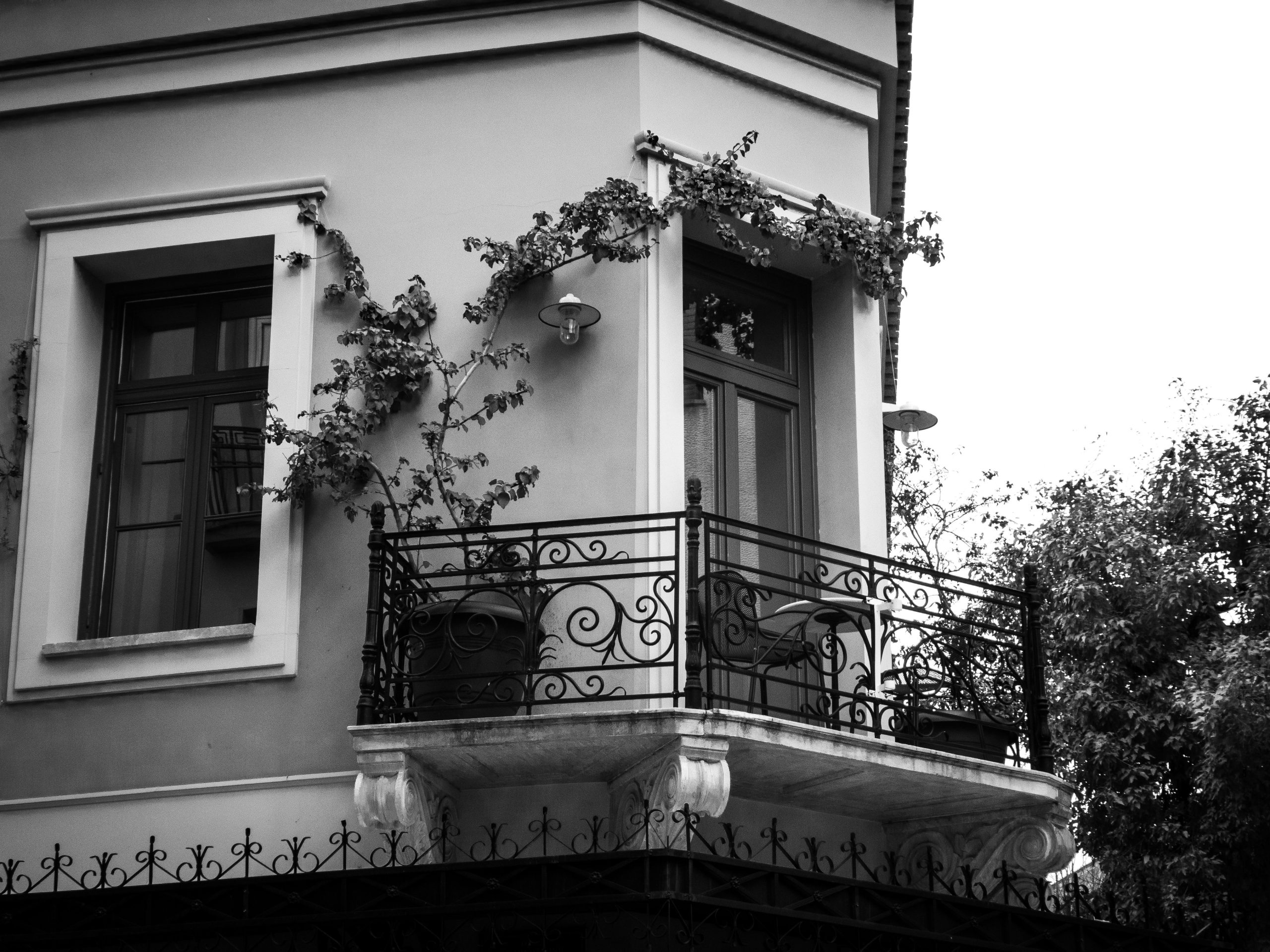 Elegant black and white photo of a classic balcony with ornate ironwork in Athens, Greece.