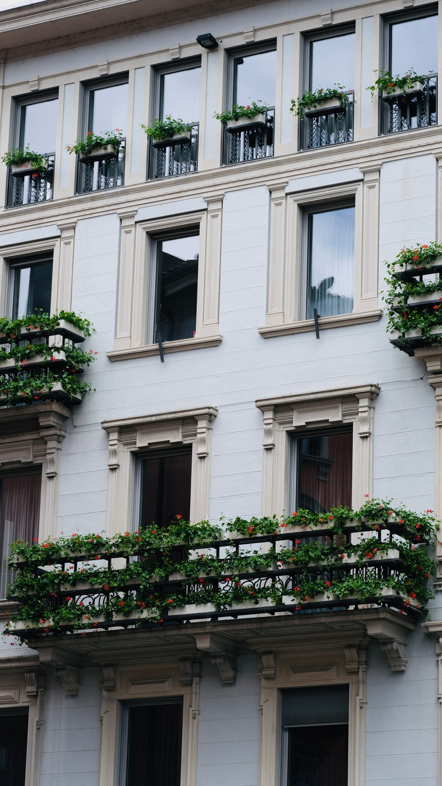 Elegant building exterior with lush green balconies adorned with plants.