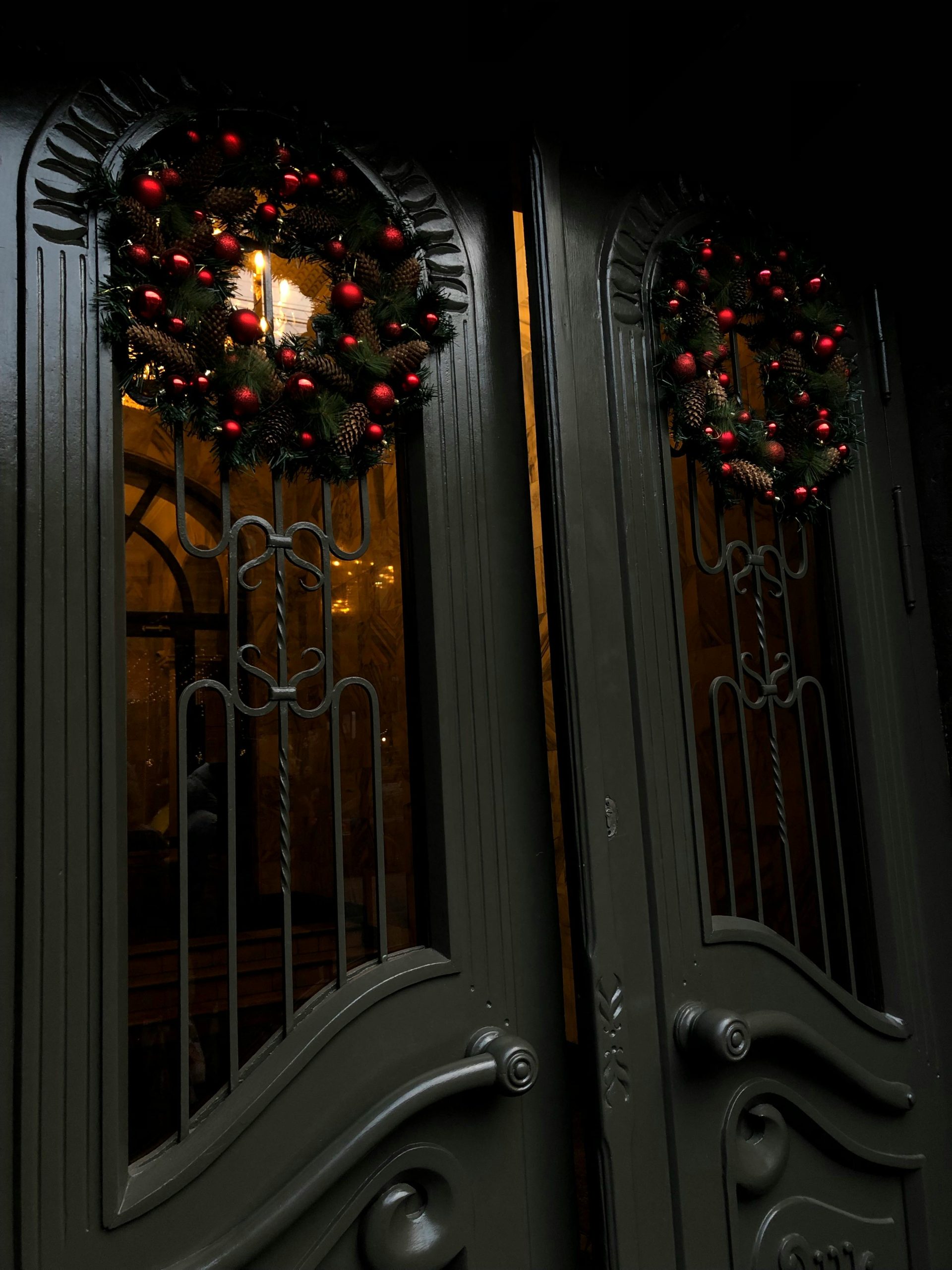 Festive Christmas wreaths with baubles adorn elegant double doors, creating a warm holiday atmosphere.
