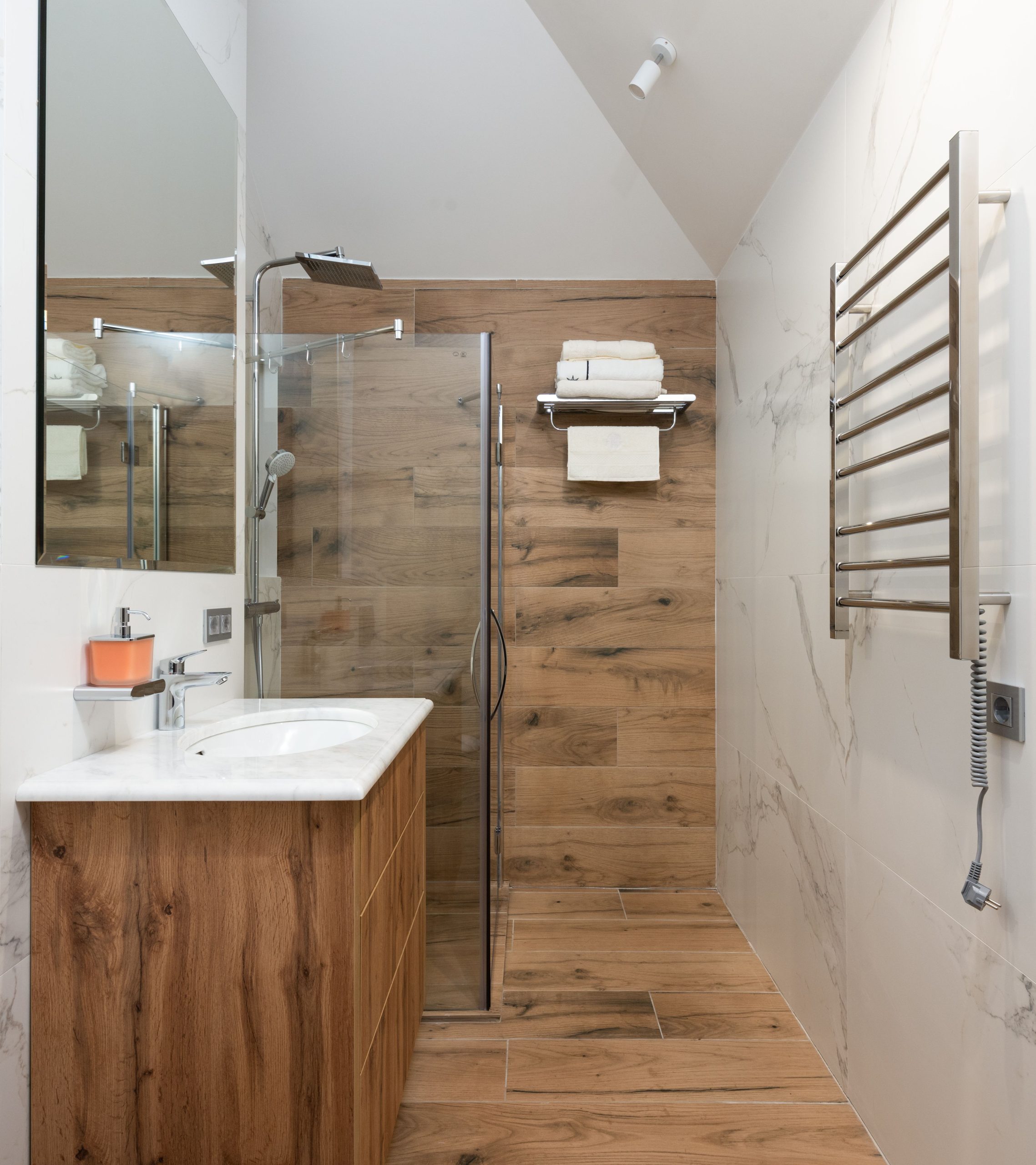 Interior of contemporary luxury bathroom with glass shower cabin and wooden modern walls