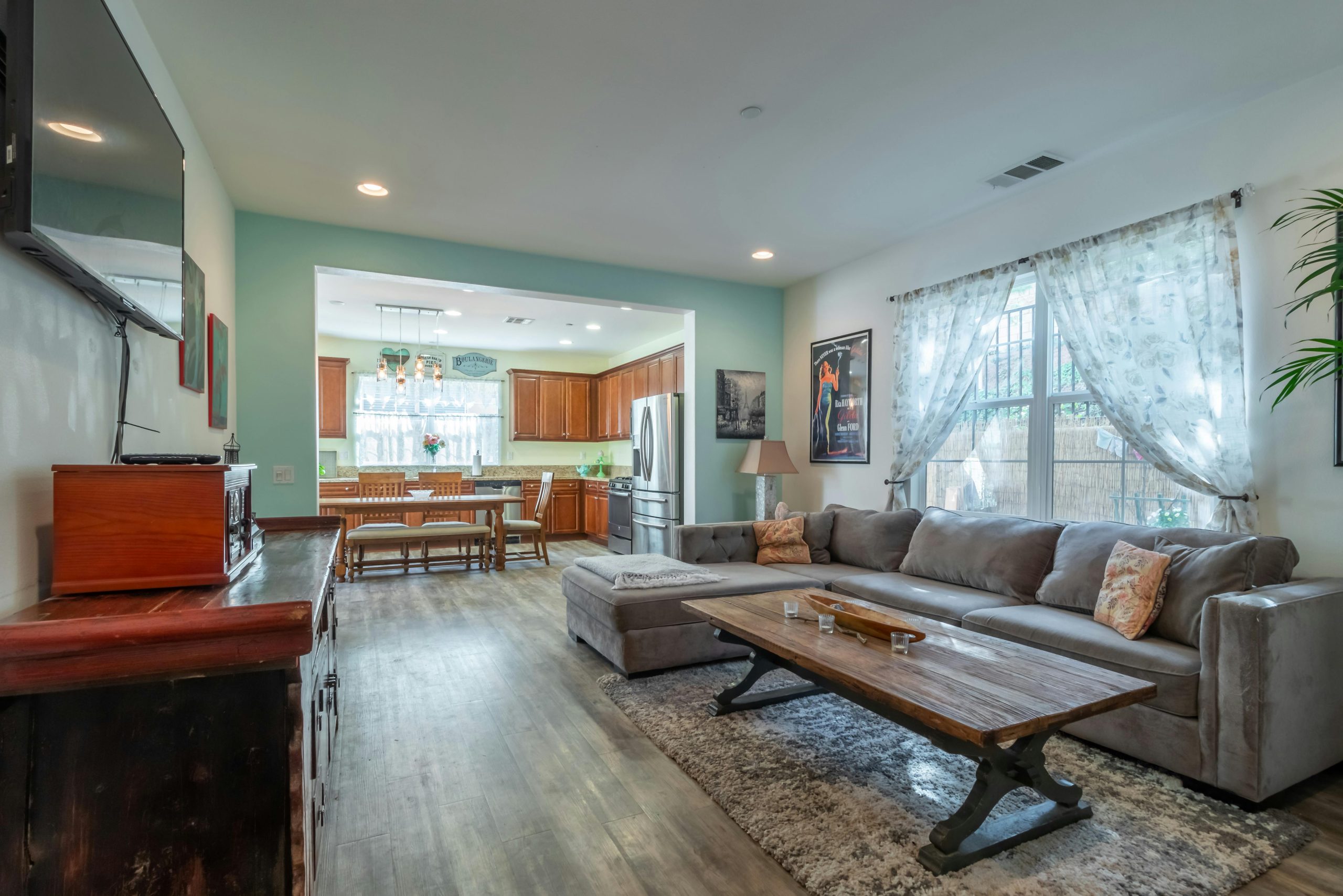 Interior of cozy living room with comfortable sofa near rustic wooden table on simple wooden floor against vintage cabinet and flat TV on wall