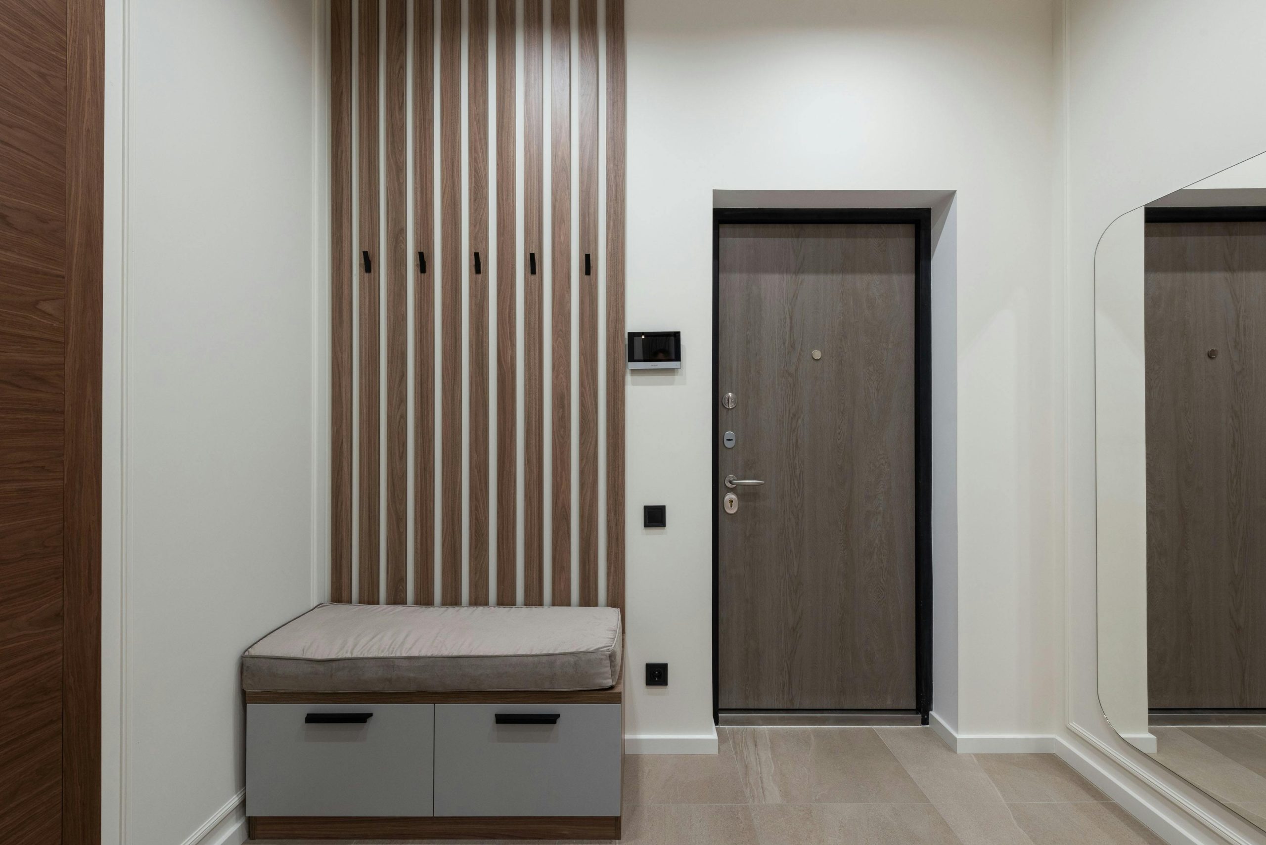 Interior of modern spacious hall with wooden cabinet with desks placed in corner and big mirror in apartment