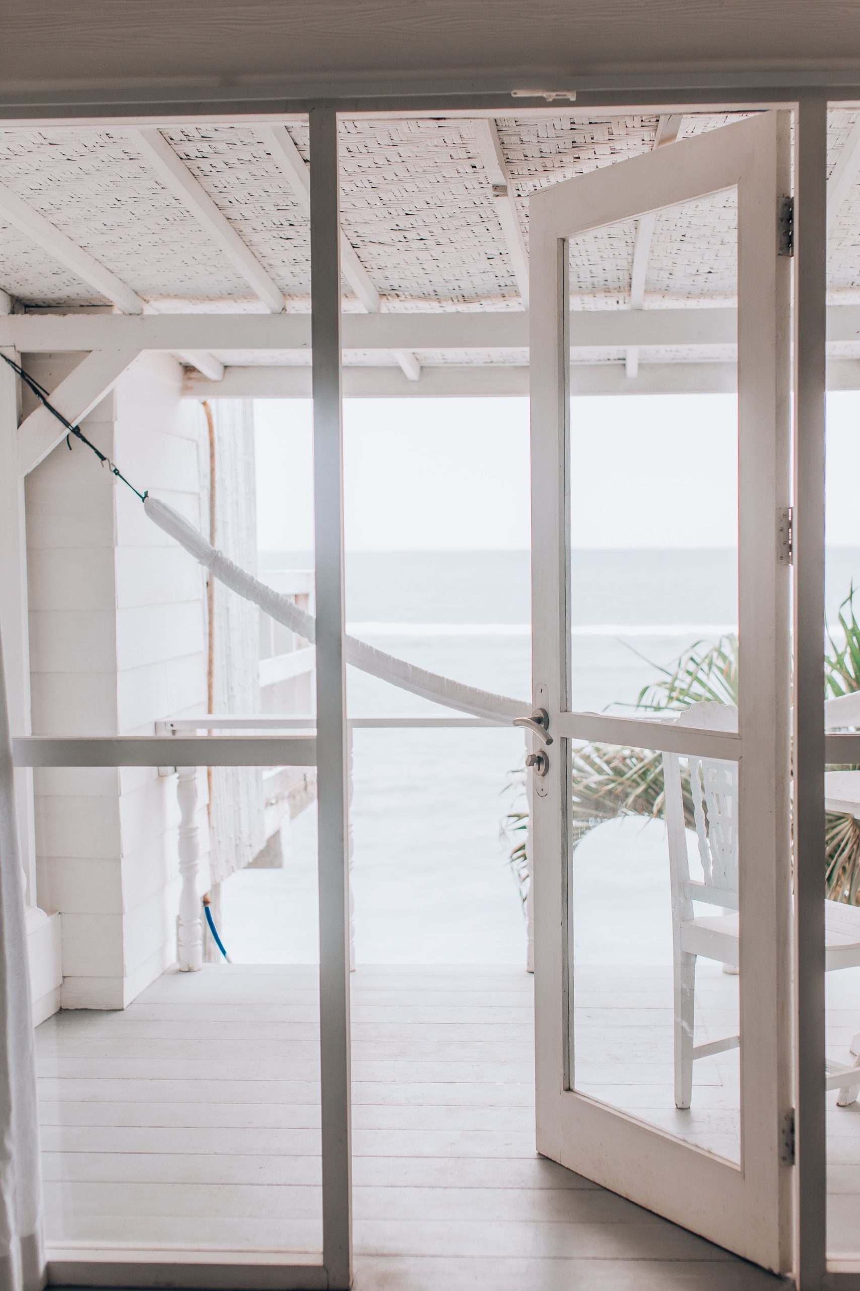 Inviting ocean view through open glass door leading to a beachside deck with calm ambiance.