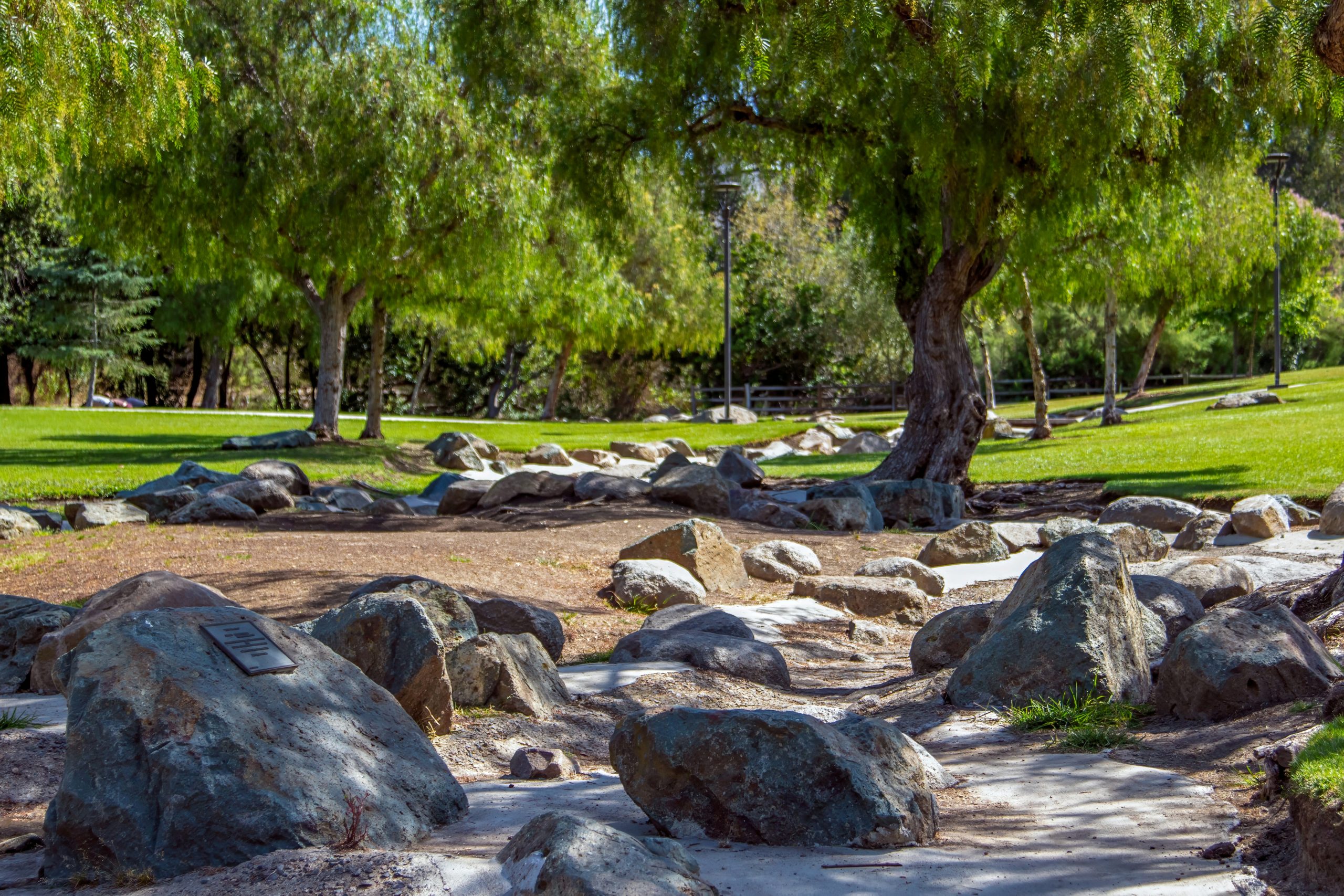 Large rocks scattered across a grassy park with green trees.