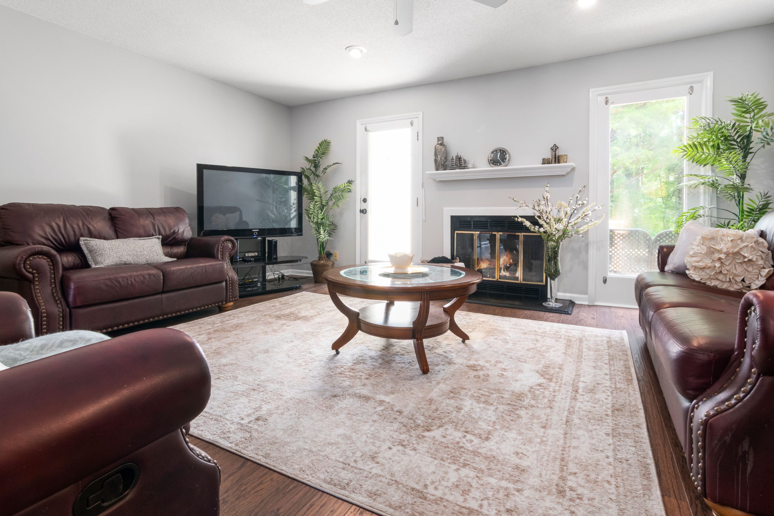 Luxurious living room featuring leather sofas, fireplace, and large windows.