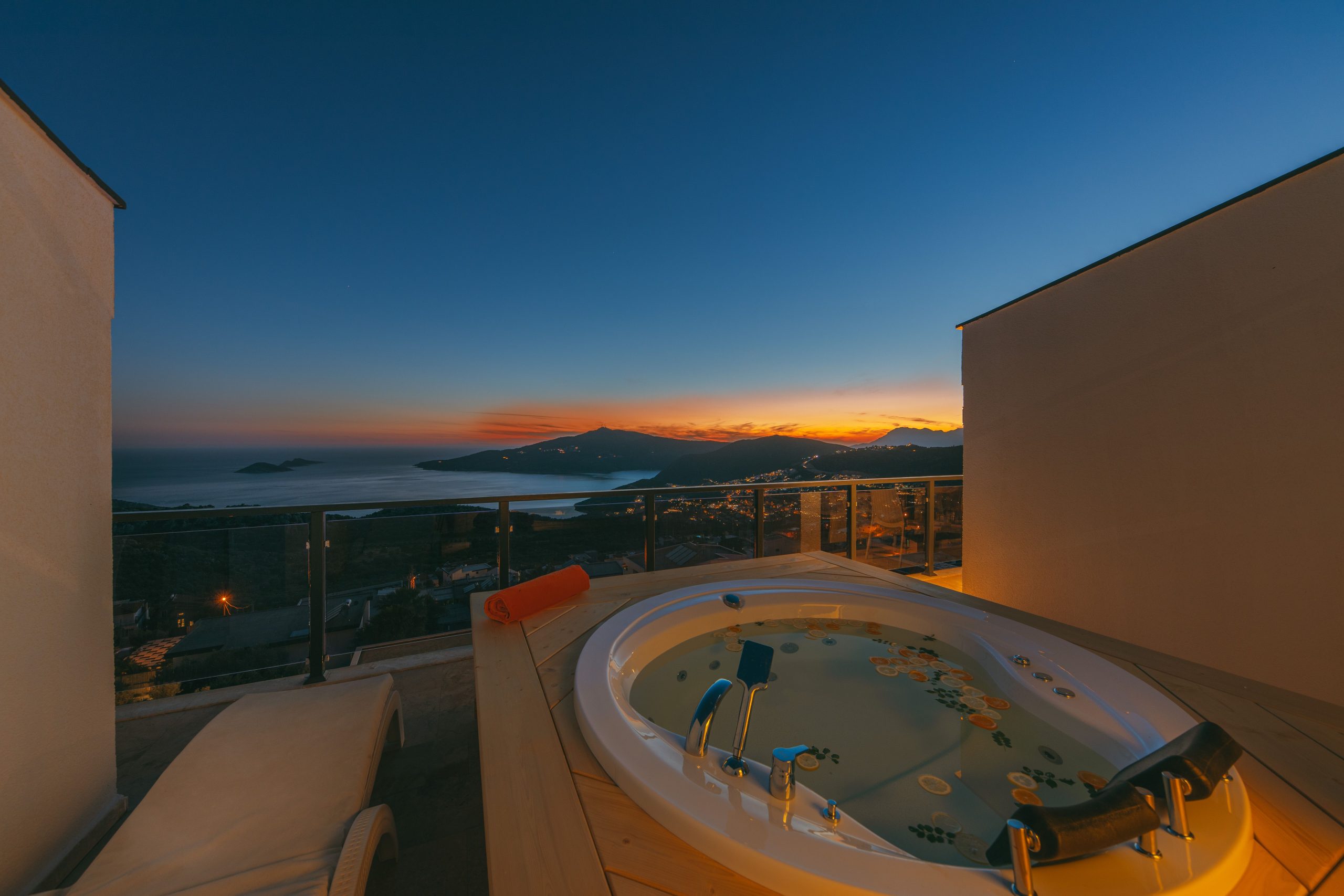 Luxury terrace with jacuzzi and scenic coastal sunset view, perfect for relaxation.