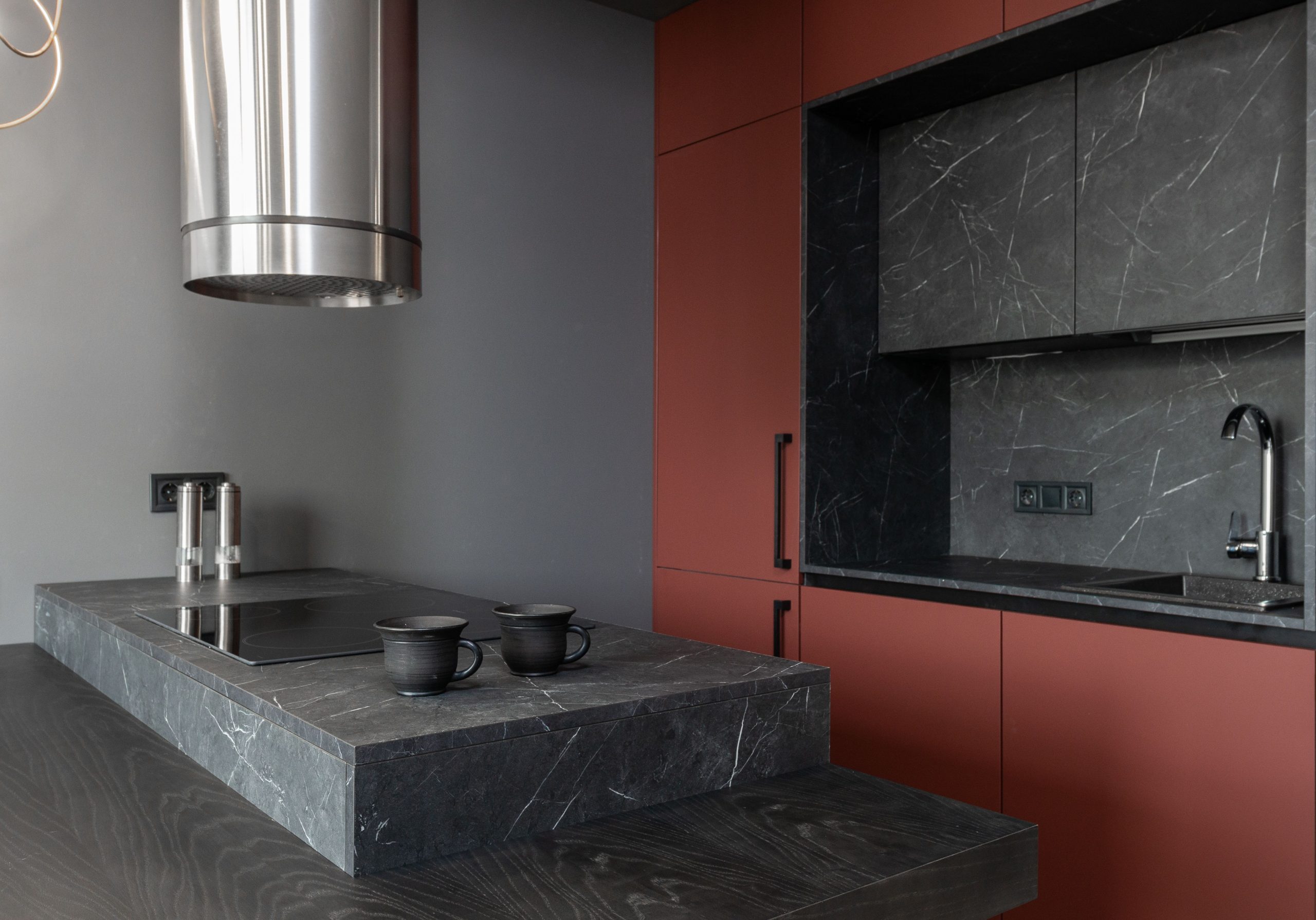 Minimalist style interior design of modern home kitchen with stove built in gray island countertop under range hood and brown cupboards
